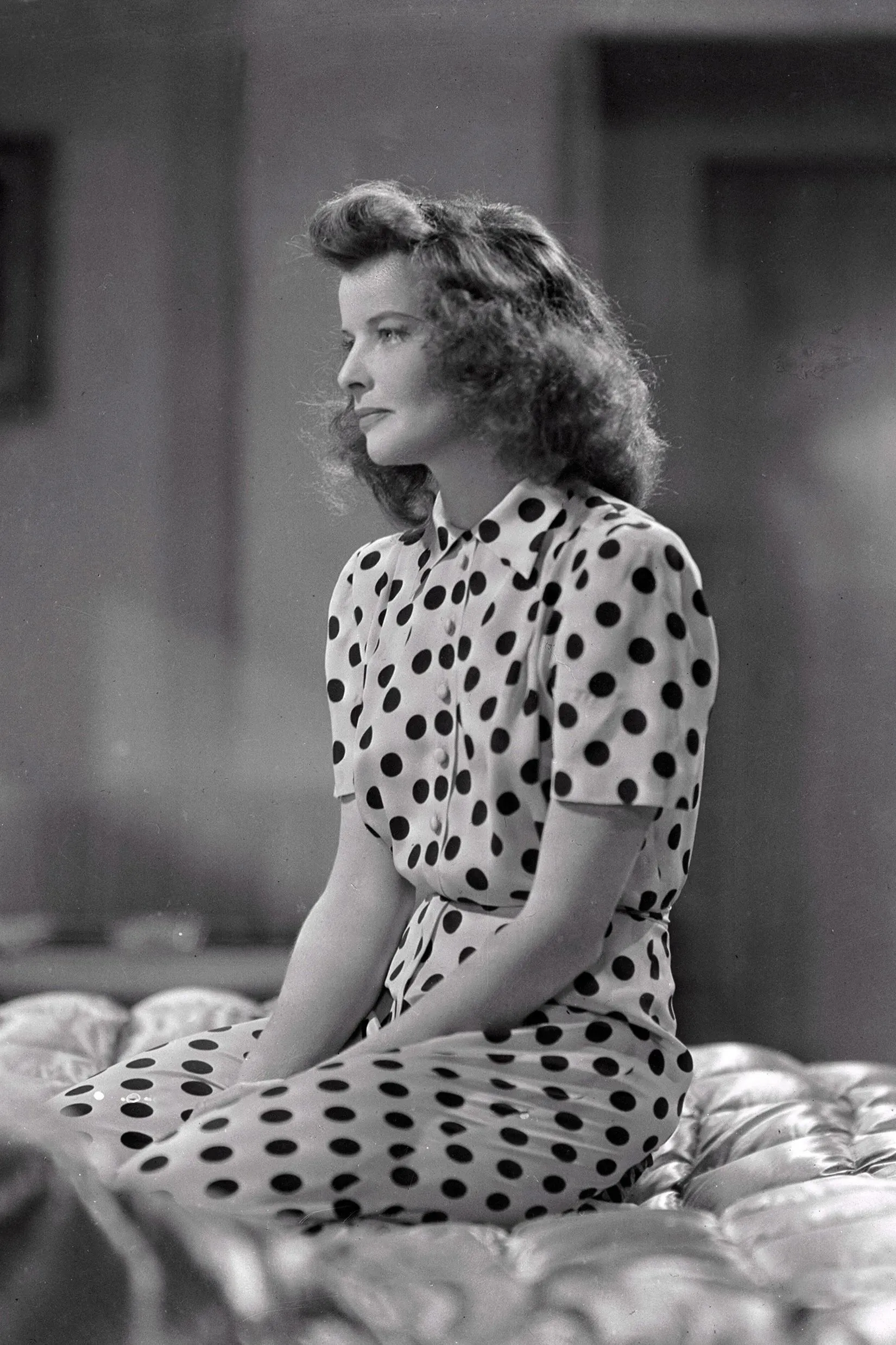 كاثرين هيبورن ترتدي فستانًا منقطًا بالأبيض والأسود في مشهد من فيلم "امرأة العام"، مما يعكس تأثير النقاط المنقطة في الموضة.