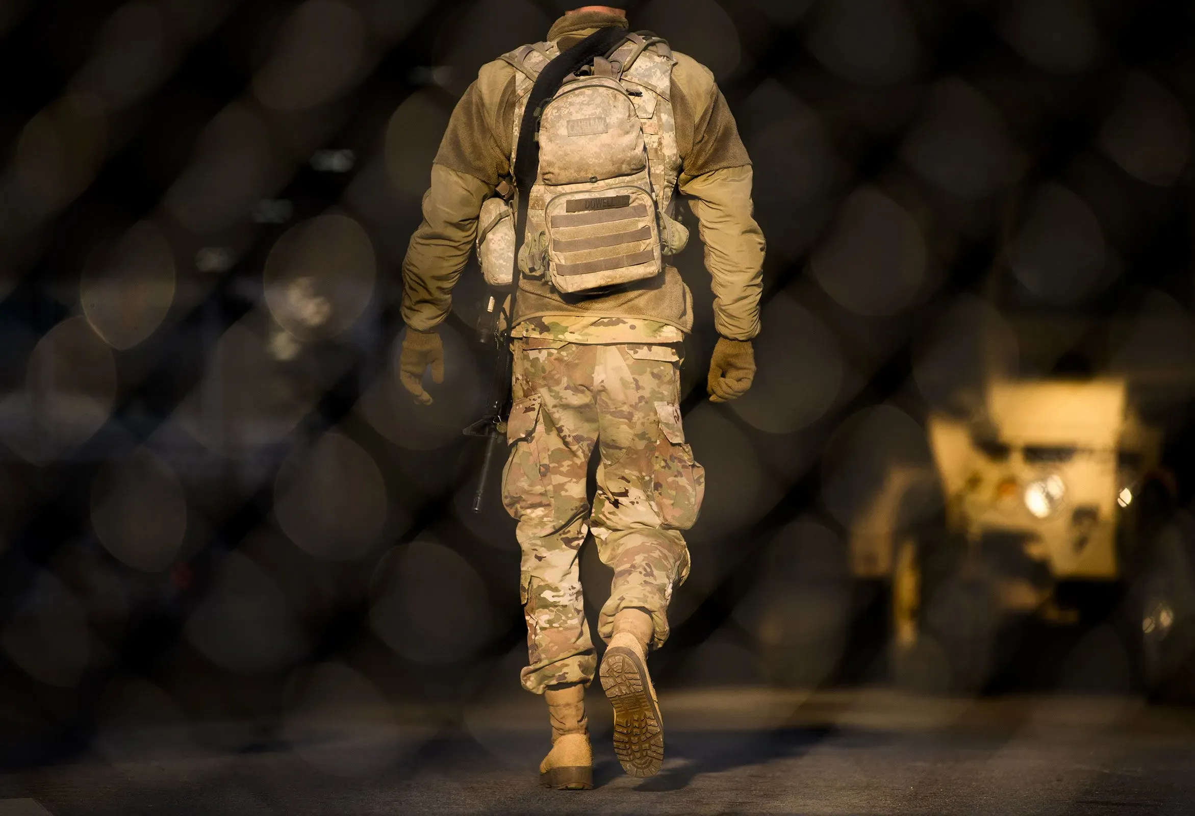 جندي يرتدي زيًا عسكريًا يسير نحو الأمام، مع وجود مركبة عسكرية في الخلفية، في سياق الاستعدادات لحفظ الأمن في المدن التوأم.