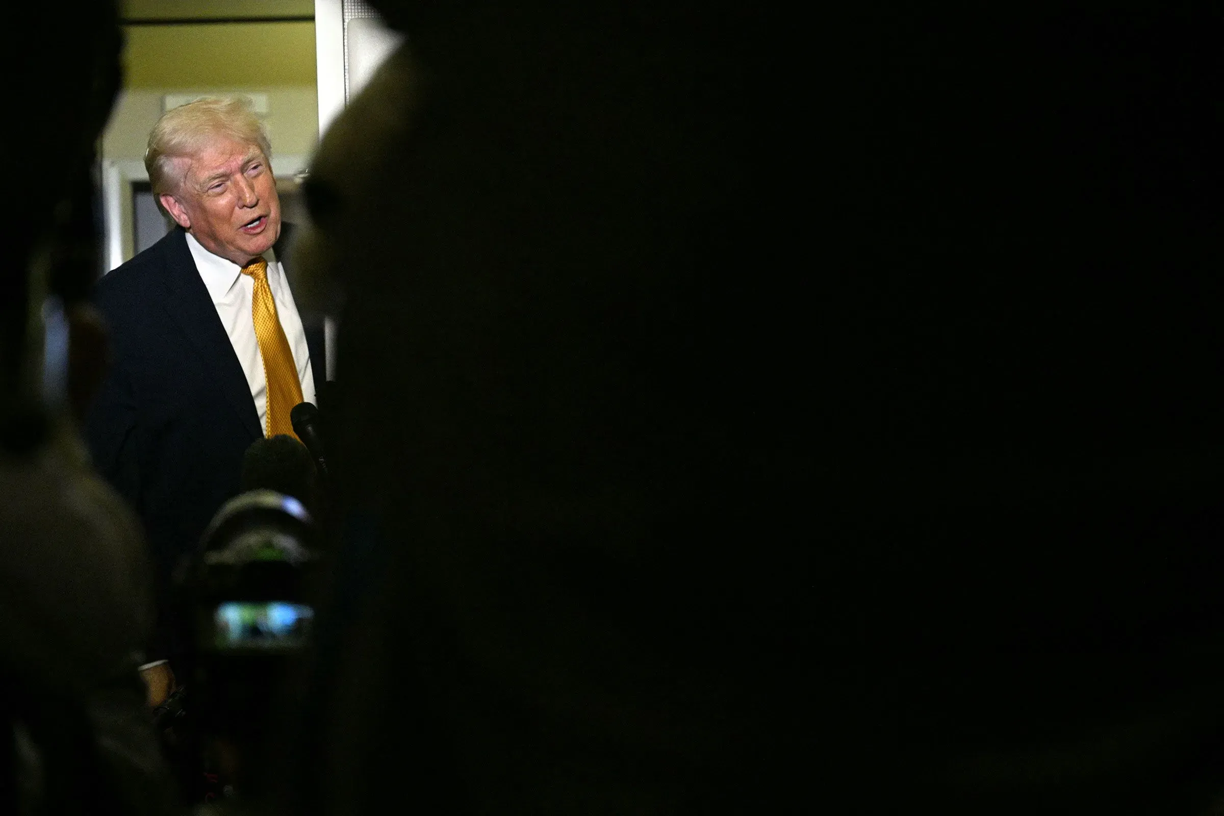 تصريح لترامب خلال مؤتمر صحفي، حيث يظهر وهو يتحدث وسط مجموعة من الصحفيين، مع التركيز على قضايا الأمن وإنفاذ القانون.