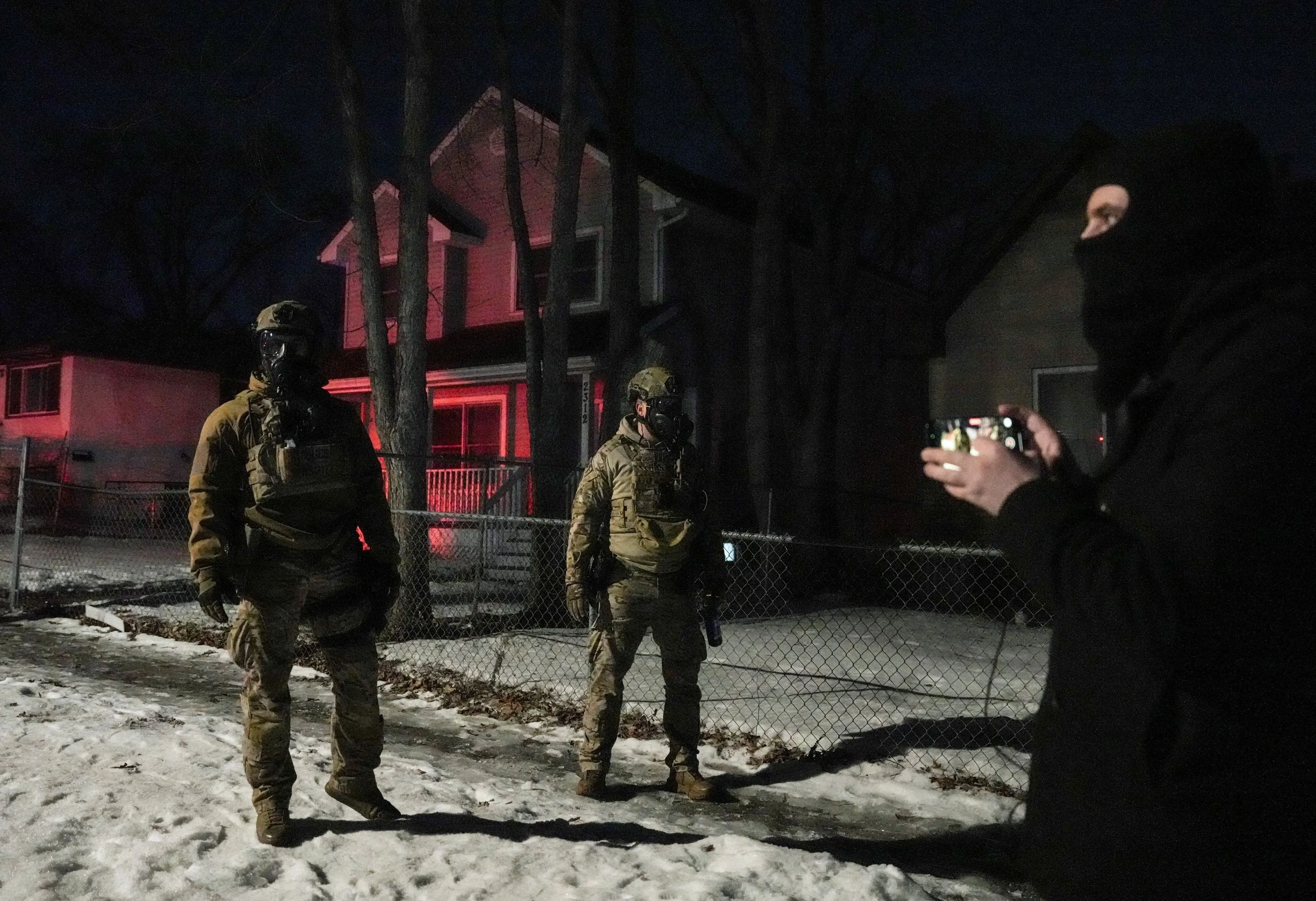 مجموعة من المراقبين القانونيين في مينيابوليس تراقب عملاء الهجرة في الليل، مع وجود ضباط يرتدون زيًا عسكريًا.