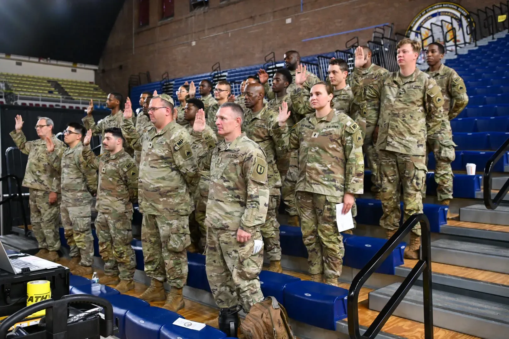 جنود من الحرس الوطني يؤدون اليمين في قاعة رياضية، وسط أجواء رسمية، استعدادًا لدعم قوات إنفاذ القانون في واشنطن.