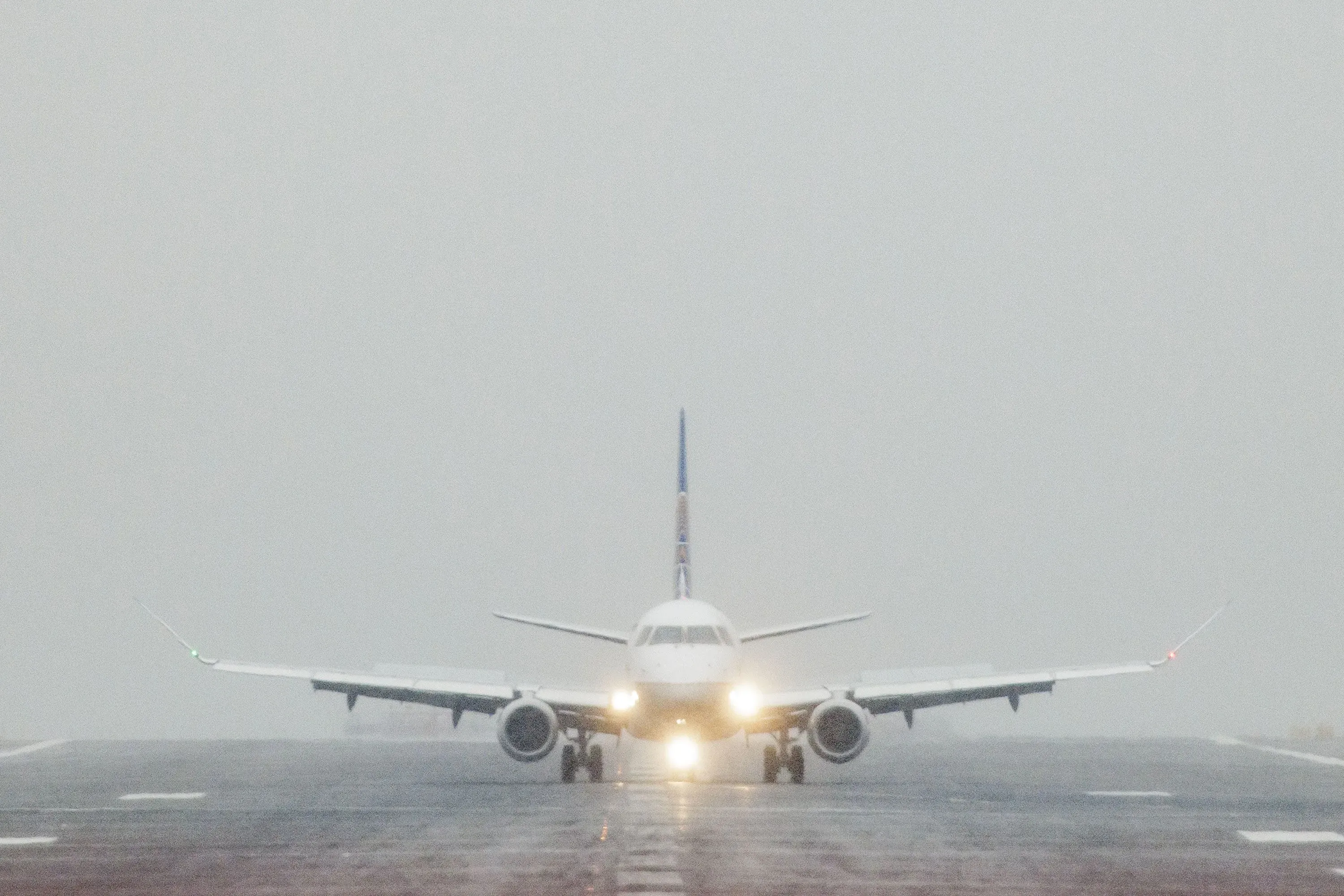 طائرة تجارية على مدرج مطار في ظروف ضبابية، مما يبرز أهمية خبراء الأرصاد الجوية في سلامة الطيران.