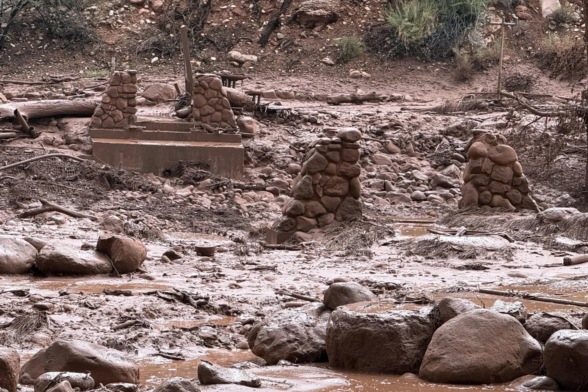 بقايا جسر حجري مدمّر وسط طين وصخور بعد فيضان نهر Bright Angel Creek قرب Phantom Ranch في Grand Canyon.