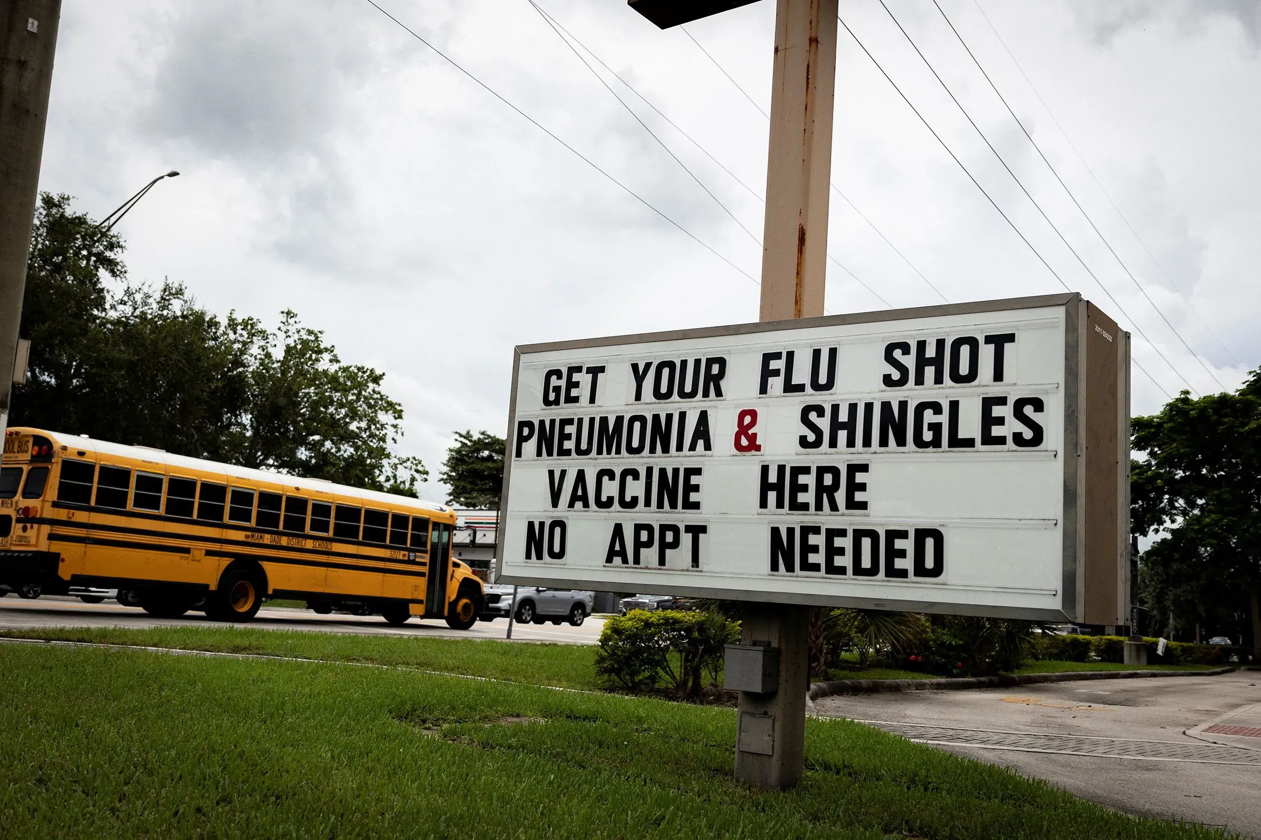 لافتة تشير إلى توفر لقاحات للإنفلونزا والالتهاب الرئوي والجدري، مع عبارة "لا حاجة لموعد"، بالقرب من حافلة مدرسية في تامبا، فلوريدا.