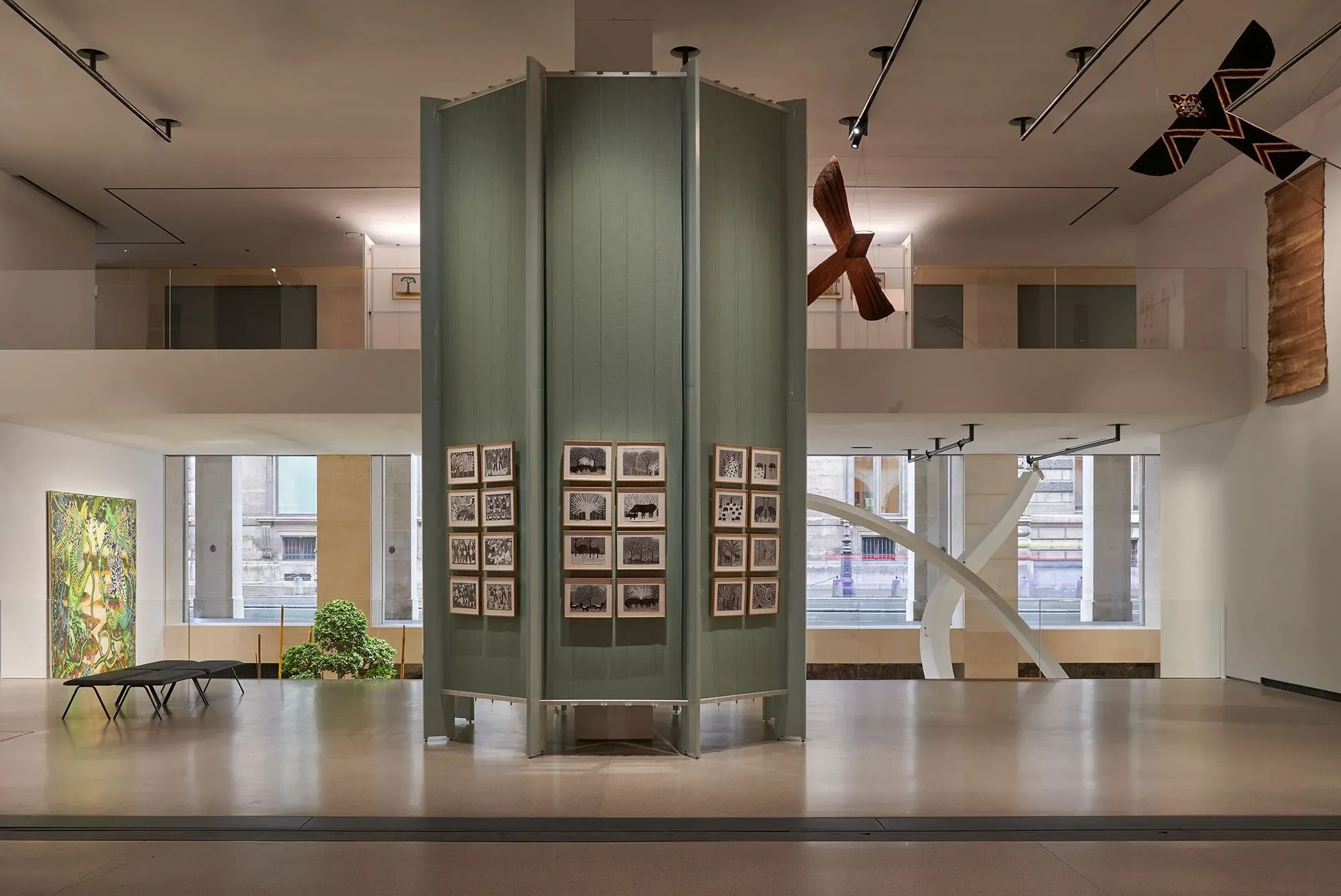 مساحة عرض حديثة في متحف مؤسسة كارتييه للفنون، تتضمن جدران خضراء ومنحوتات معاصرة، تُبرز تفاعل الفن مع التصميم المعماري.