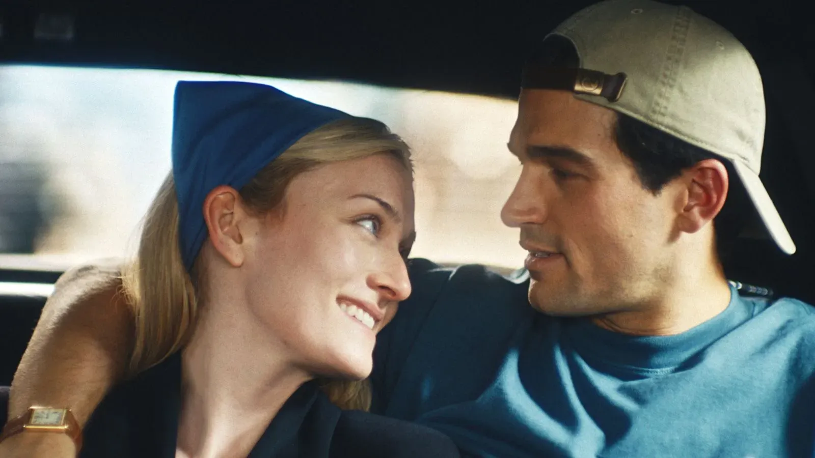 لقطة من مسلسل "قصة حب" تظهر جون كينيدي جونيور وكارولين بيسيت كينيدي في لحظة حميمة داخل السيارة، تعكس حياتهما العاطفية.