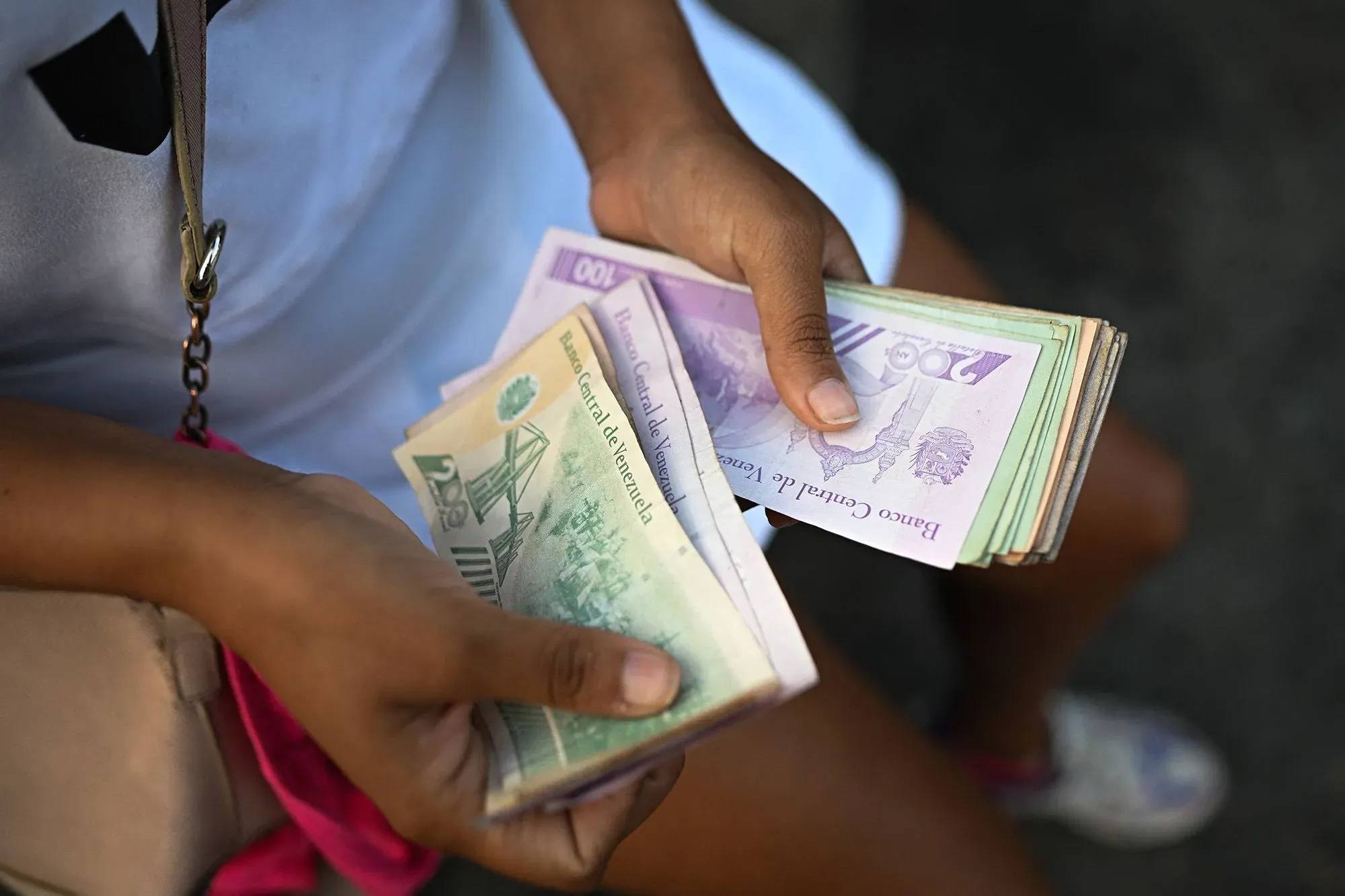 يد تحمل مجموعة من الأوراق النقدية الفنزويلية، تعكس التحديات الاقتصادية اليومية التي يواجهها المواطنون في ظل التضخم.