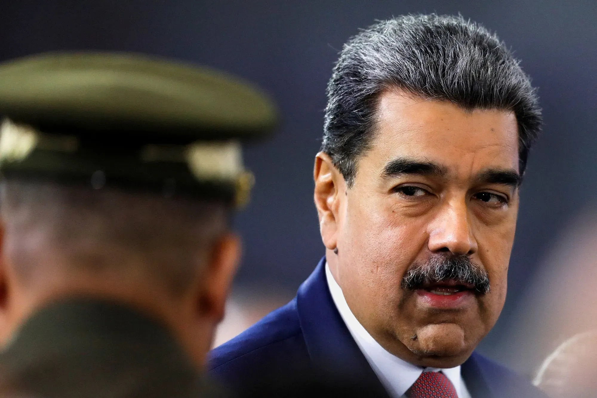 صورة لنicolas مادورو، رئيس فنزويلا، يتحدث مع مسؤول عسكري، تعكس التوترات السياسية في البلاد وتأثيرها على الحياة اليومية للفنزويليين.
