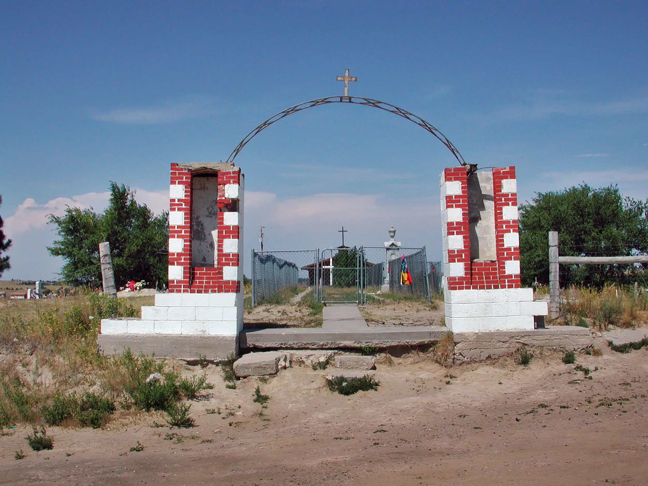 مدخل موقع الركبة الجريحة، مع أعمدة حمراء وبيضاء وصليب، يرمز إلى ذكرى المذبحة التي وقعت في ديسمبر 1890.