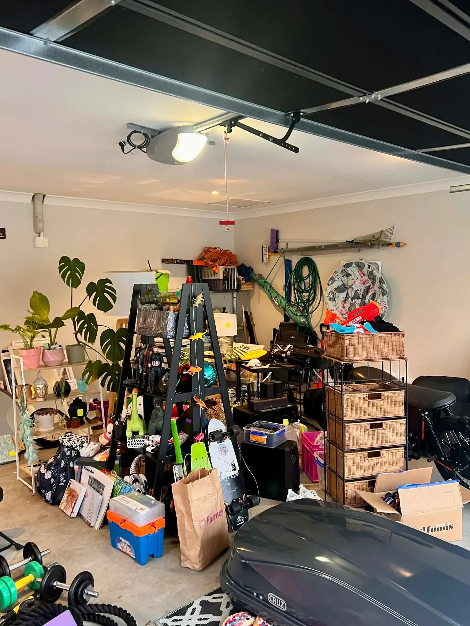 مرآب مزدحم بالأغراض المتنوعة، بما في ذلك معدات التخييم، كتب، ودُمى، مما يعكس حياة عائلة ثورن بعد انتقالهم إلى أستراليا.