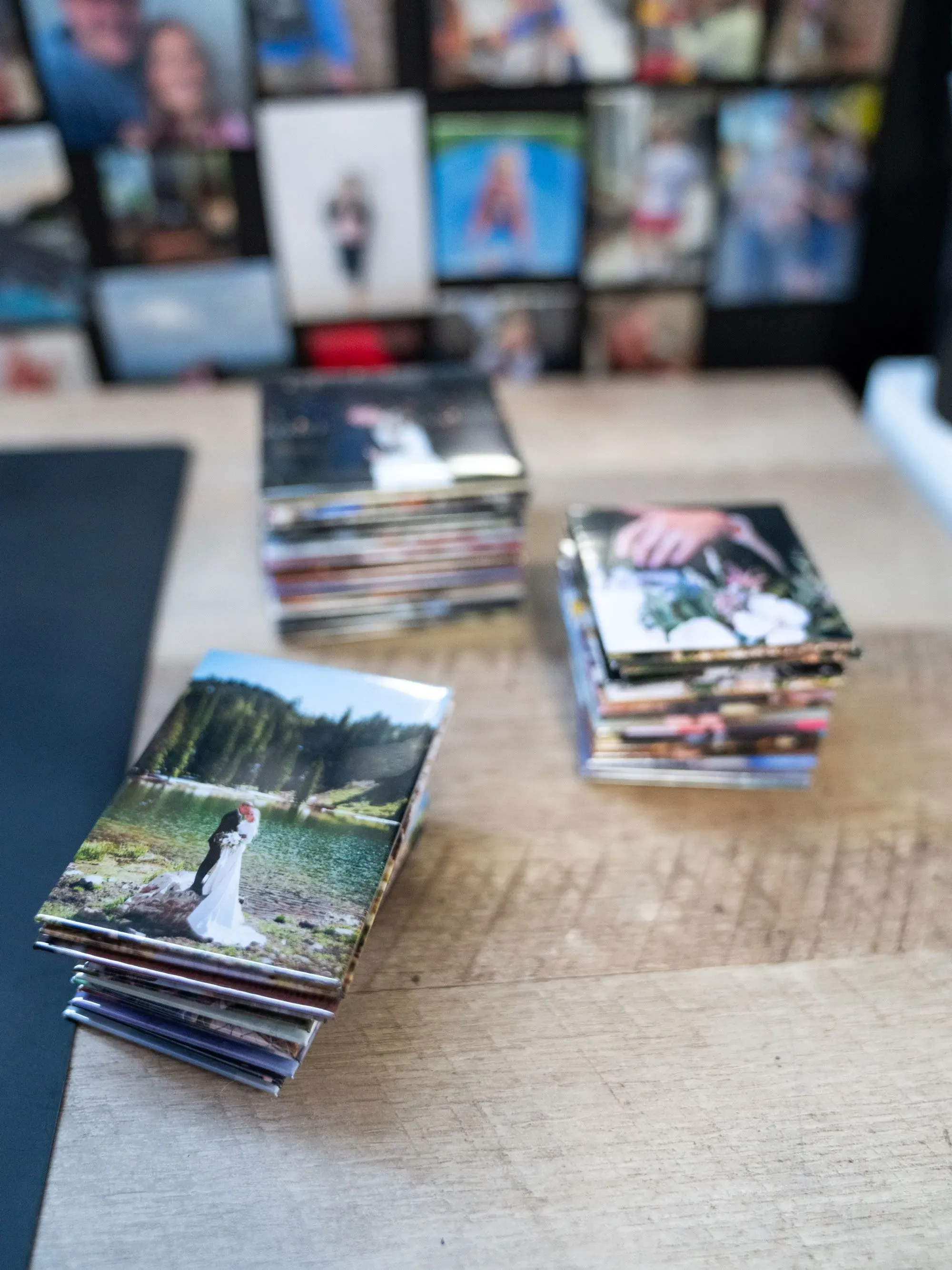 صور ملونة مطبوعة من حفلات الزفاف، موضوعة بشكل مرتب على طاولة خشبية، تعكس لحظات سعيدة للعرسان والضيوف.