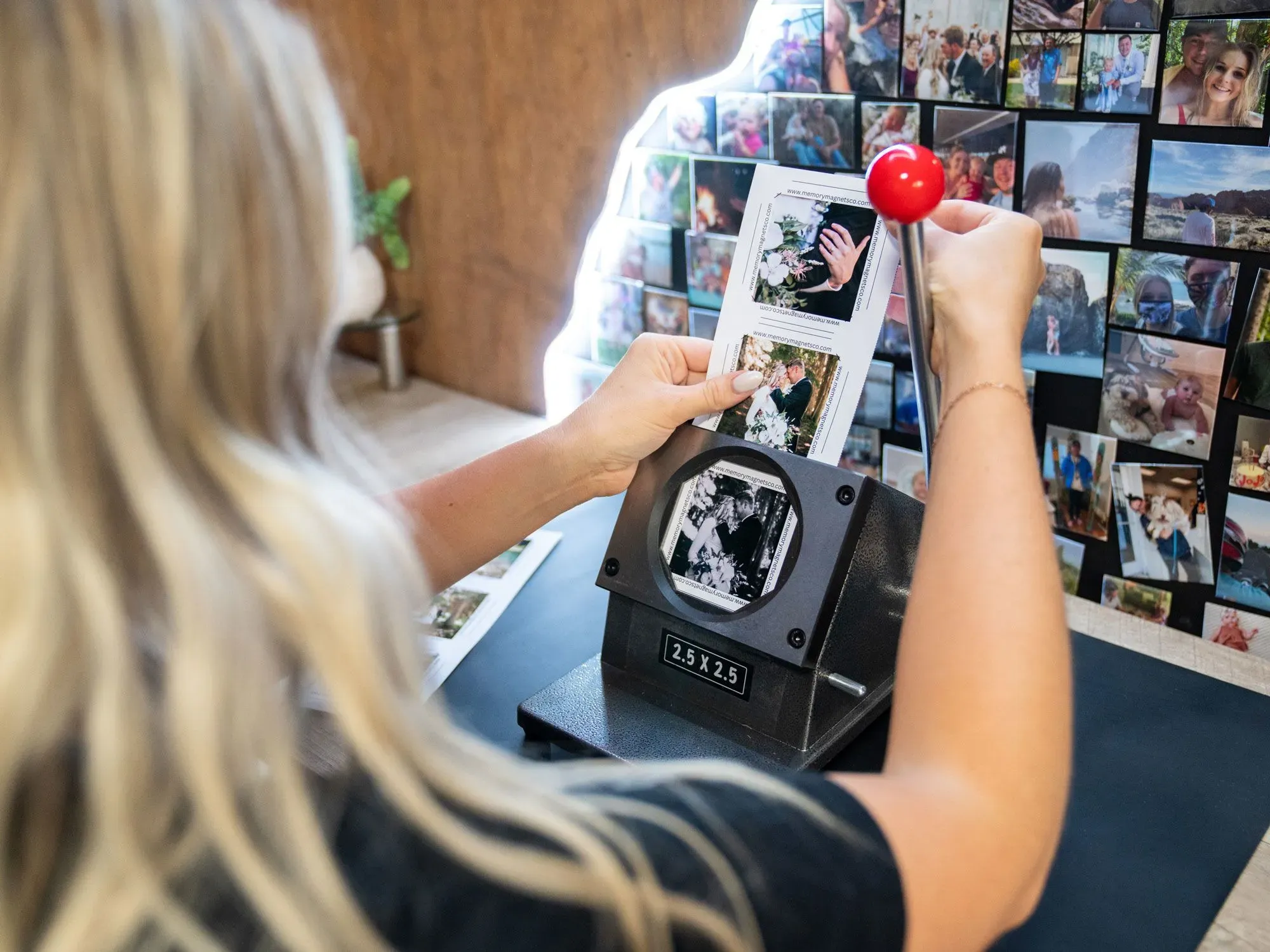 امرأة تستخدم آلة طباعة صور في كشك تصوير، محاطة بصور زفاف ملصقة على الحائط، تعكس أجواء حفلات الزفاف في جنوب كاليفورنيا.