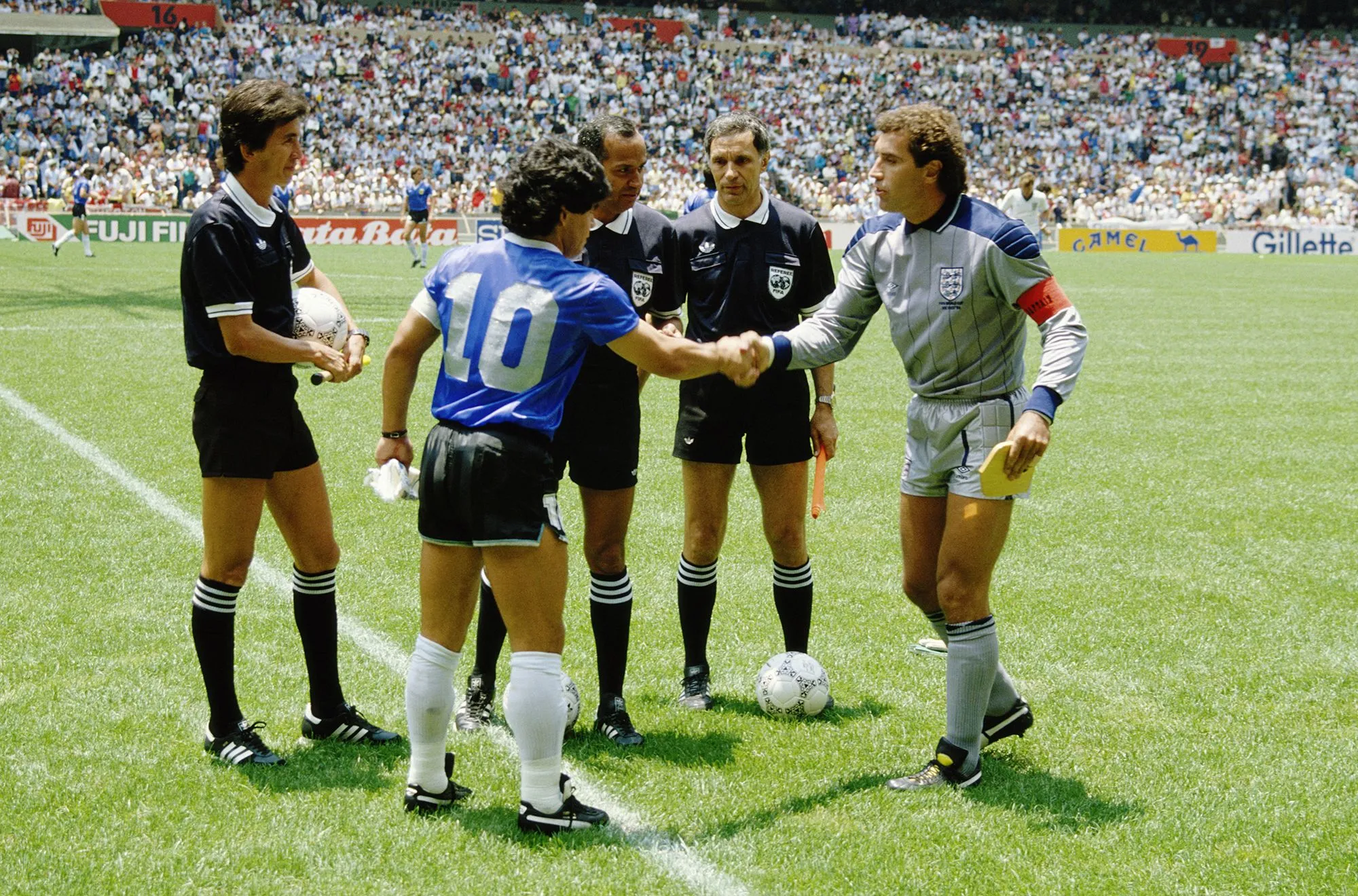 دييغو مارادونا قائد الأرجنتين يصافح قائد إنجلترا قبل مباراة كأس العالم 1986 وسط حضور الحكام في ملعب مكتظ بالجماهير.