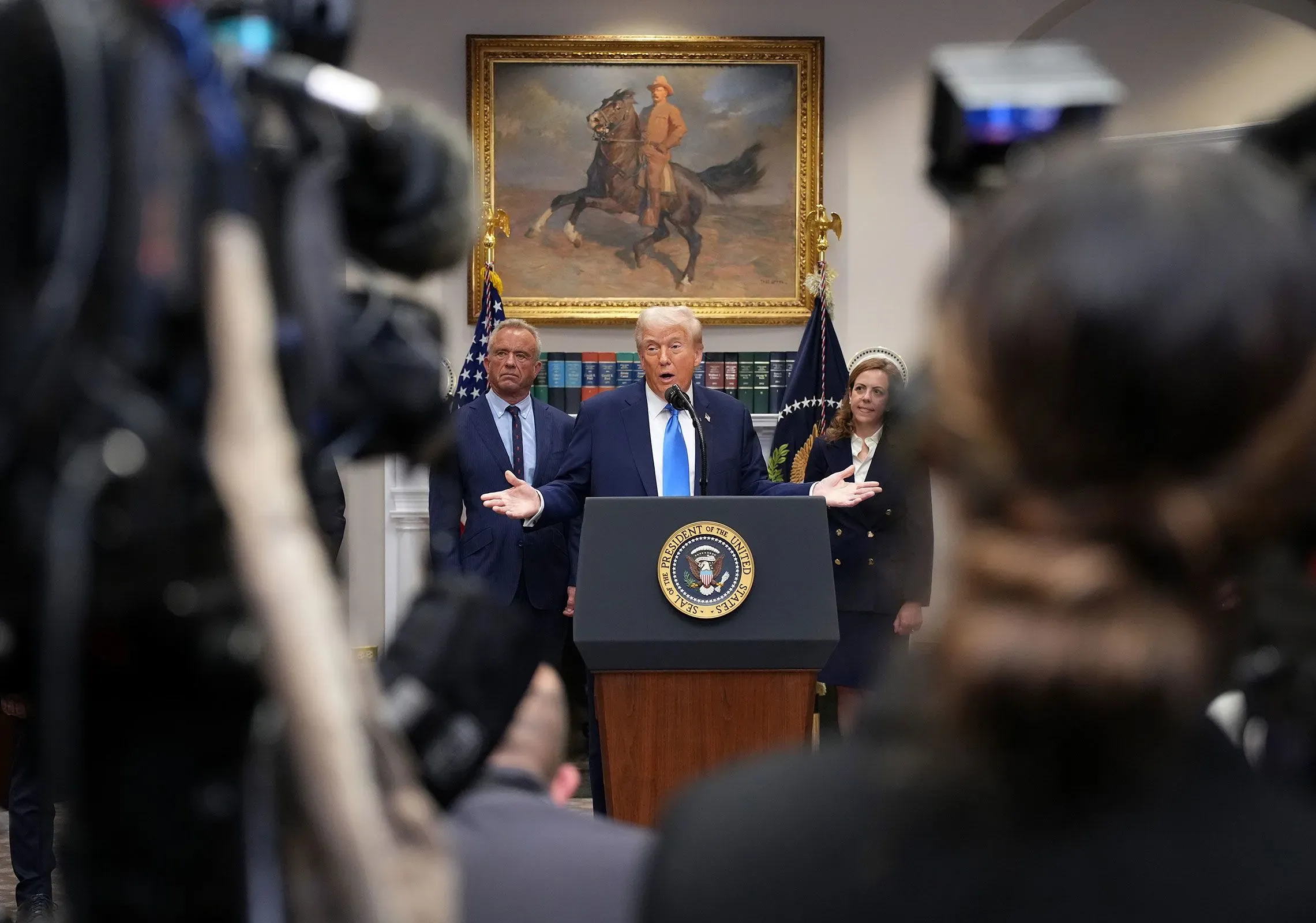 تصريح الرئيس ترامب حول تايلينول وتأثيره على النساء الحوامل، مع ظهور شخصيات بارزة خلفه في مؤتمر صحفي.