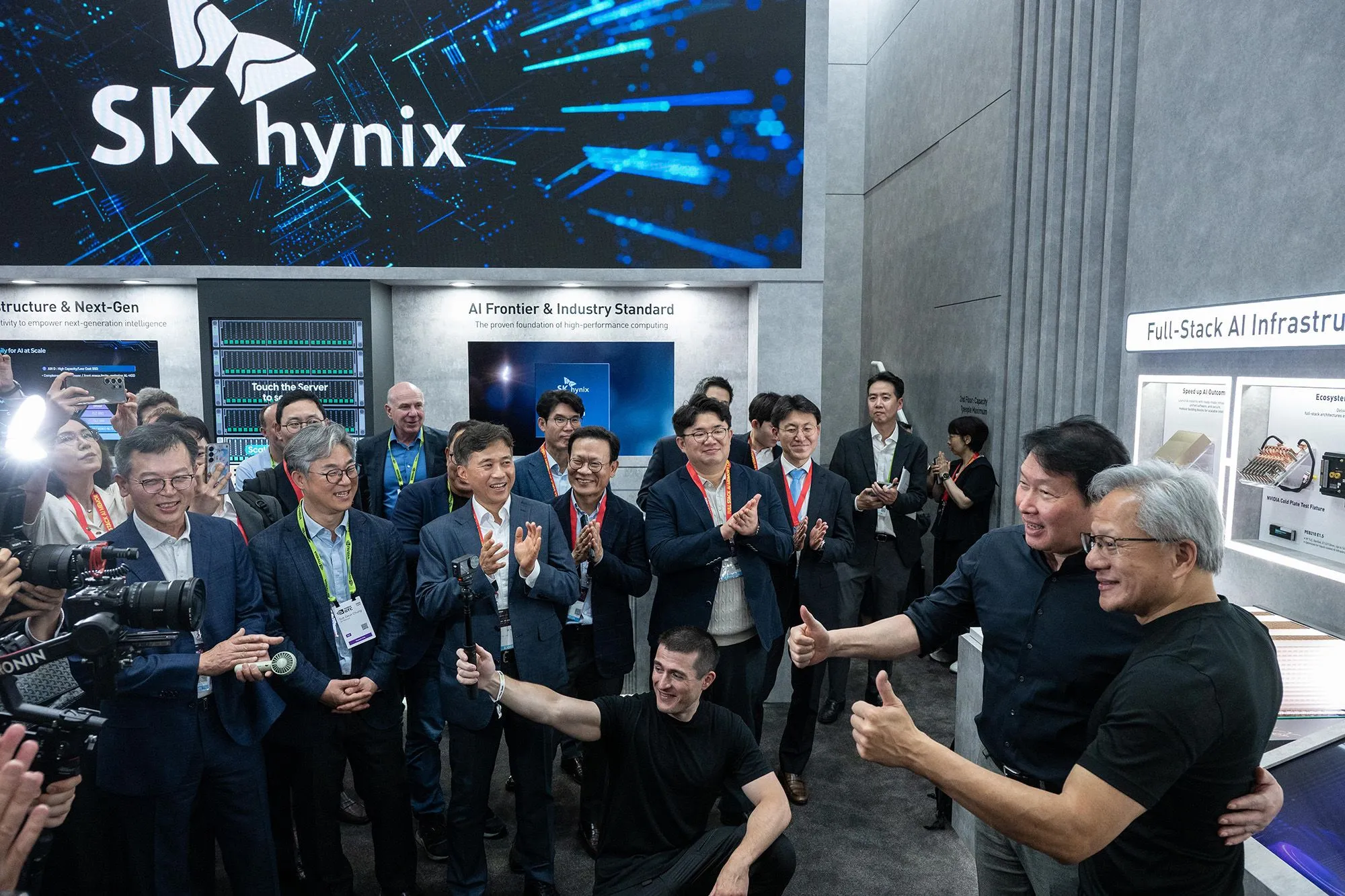 مجموعة من رجال الأعمال والمختصين في معرض تكنولوجي أمام شعار SK Hynix، يعكس التنافس والتعاون بين كوريا الجنوبية وتايوان في صناعة رقائق الذكاء الاصطناعي.