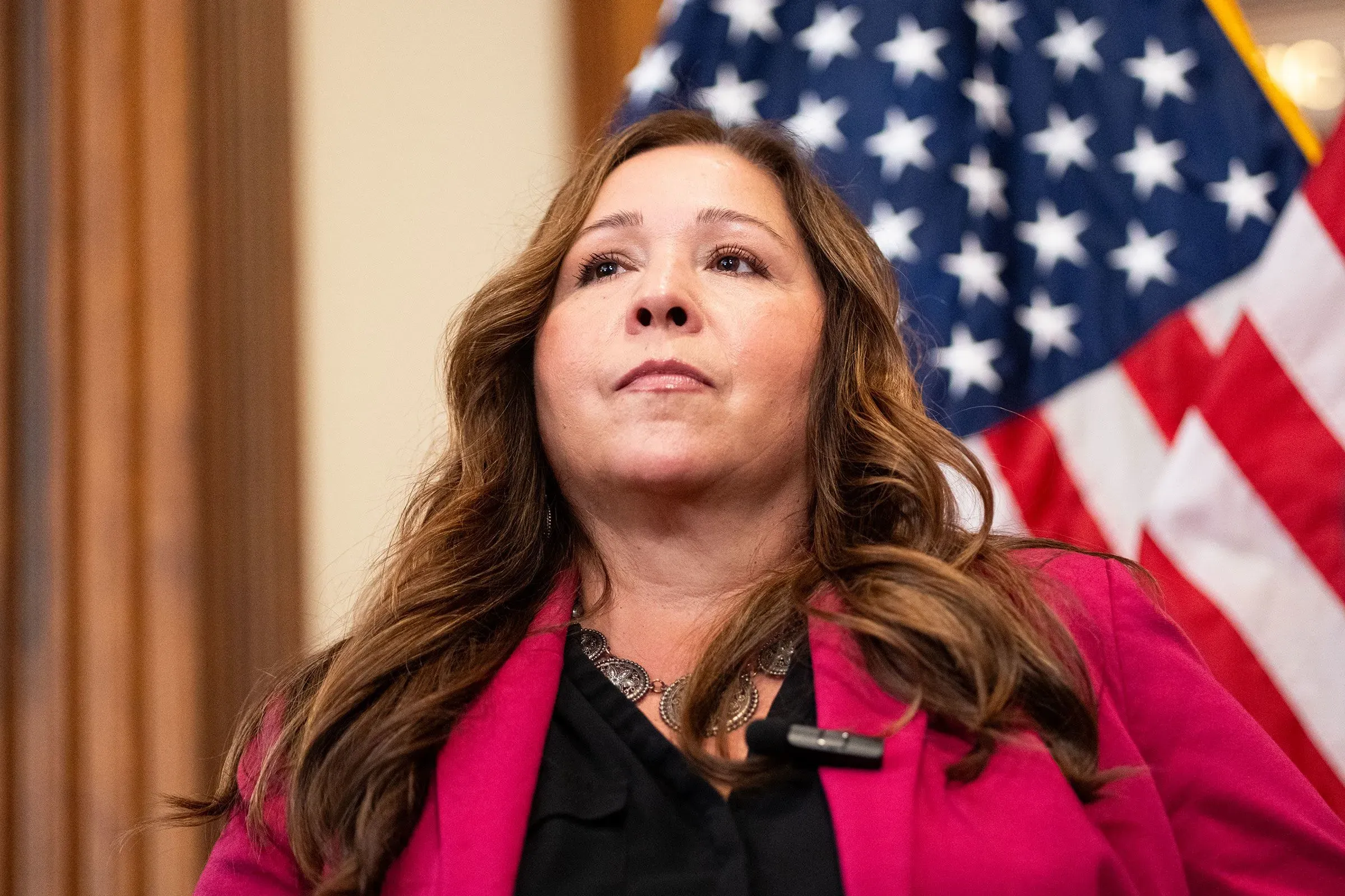 أديليتا جريجالفا، النائبة الجديدة عن أريزونا، تبدو عازمة في مواجهة التحديات السياسية بعد وفاة والدها. خلفها، ترفرف الأعلام الأمريكية.