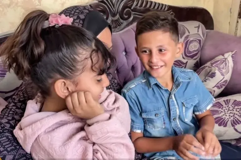 صورة لإلهام أبو حجاج (9 سنوات) مع شقيقها وأحد أقاربها، يجلسون معًا في منزلهم بعد فقدان والديهم في القصف الإسرائيلي على غزة.