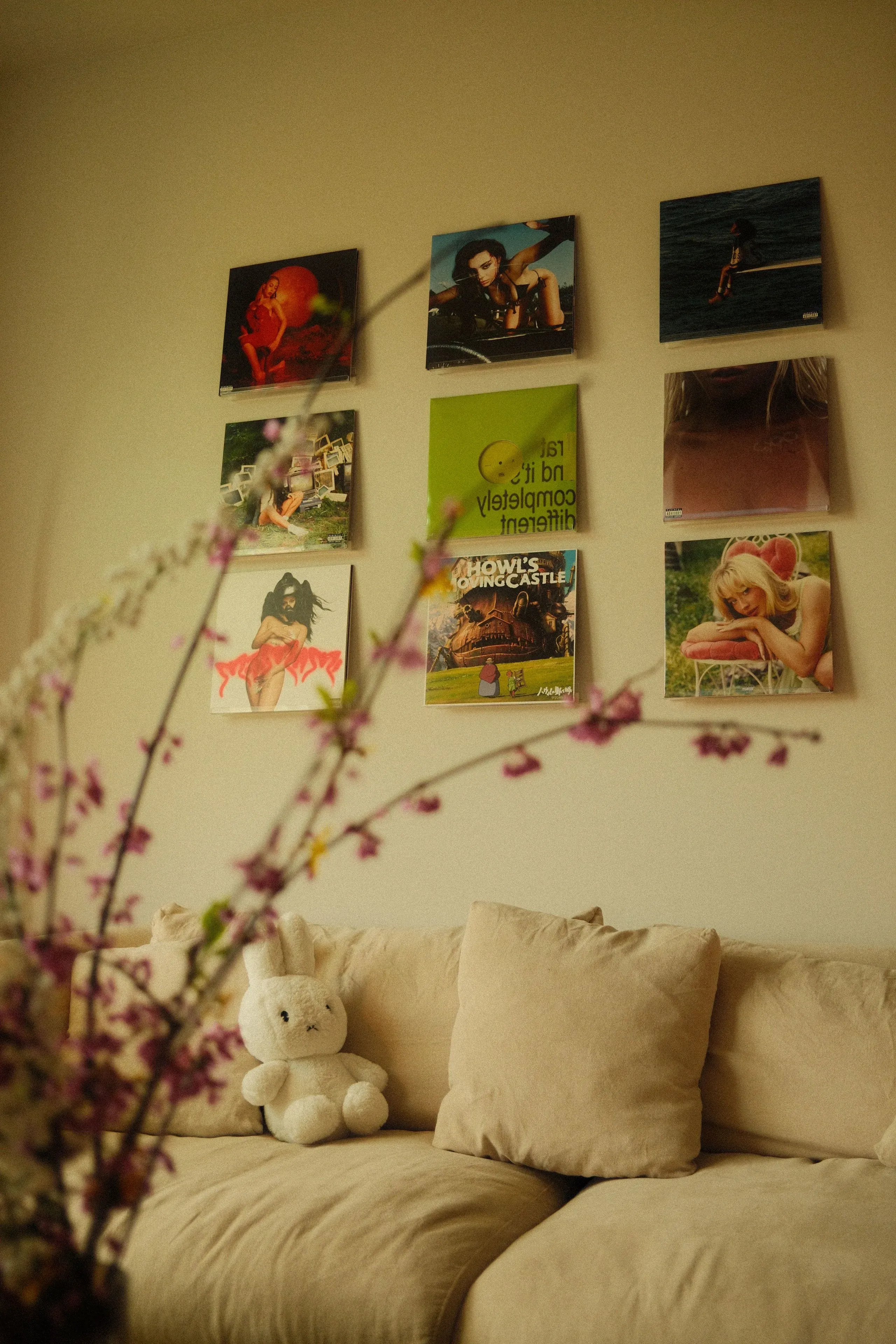 مجموعة من أسطوانات الفينيل معلقة على الحائط كديكور، مع أريكة بيج ودب محشو، تعكس شغف الجيل Z بالموسيقى والفن.