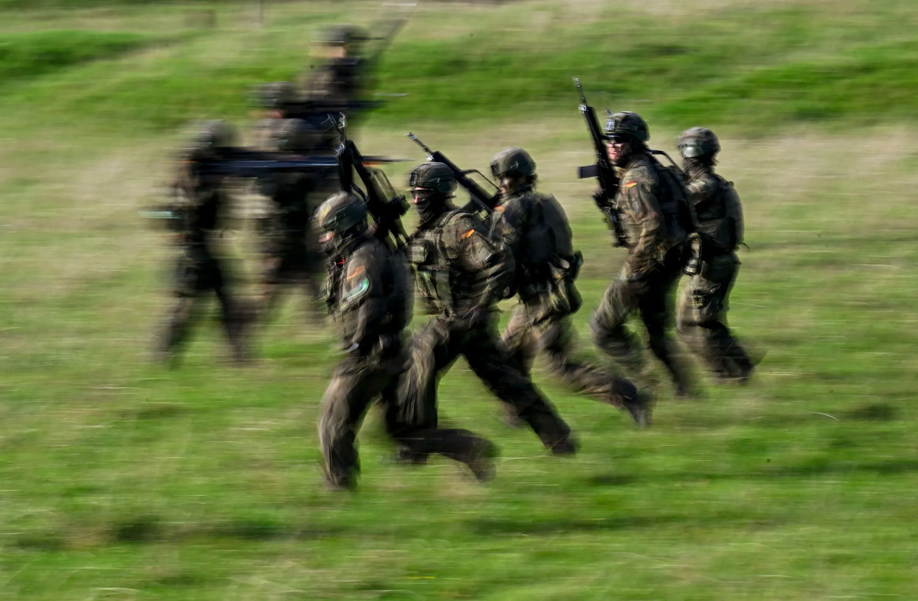 جنود ألمان يرتدون زيهم العسكري ويجرون في حقل مفتوح خلال تدريبات عسكرية، في سياق تعزيز القوات لمواجهة التهديدات الأمنية.