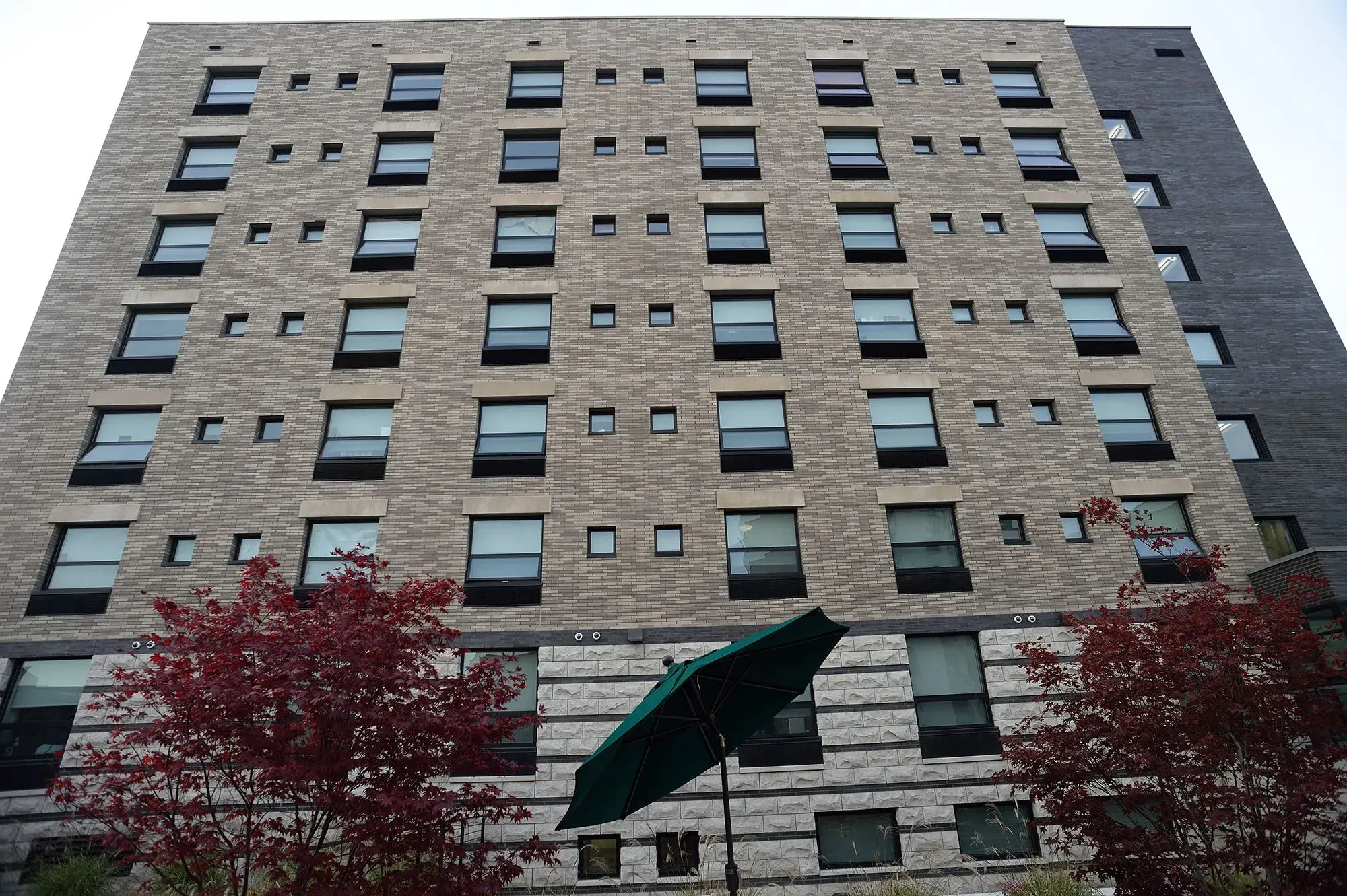 واجهة مبنى سكني حديث يتكون من عدة نوافذ، مع شجرة في المقدمة، يمثل نموذج الإسكان أولًا لدعم المشردين.