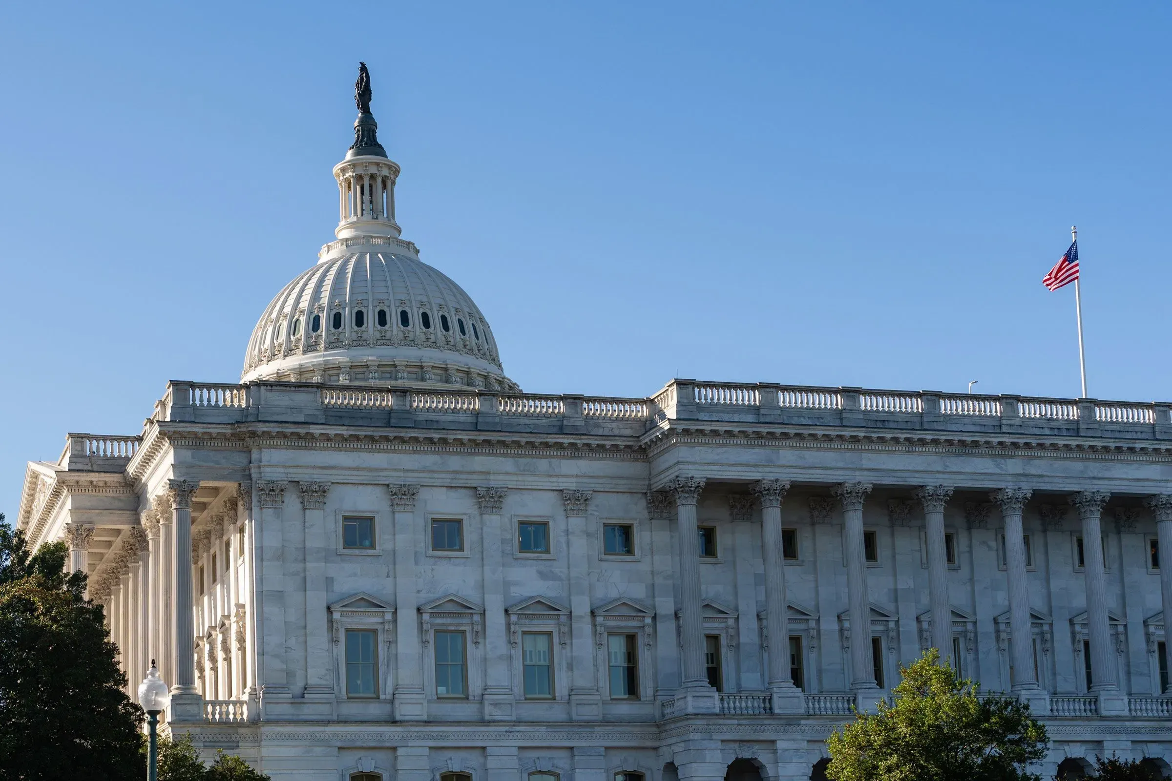 مبنى الكابيتول الأمريكي يظهر تحت سماء زرقاء، مع العلم الأمريكي يرفرف على السارية. الصورة تعكس القلق الجمهوري بشأن الرعاية الصحية.