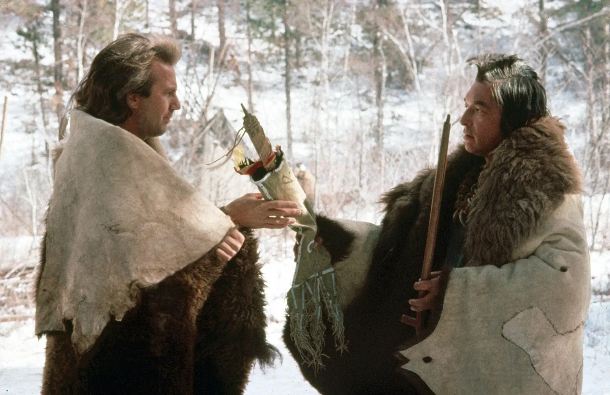 غراهام غرين في مشهد من فيلم "الرقص مع الذئاب"، حيث يتفاعل مع شخصية أخرى في إطار تاريخي يعكس الثقافة الأصلية.