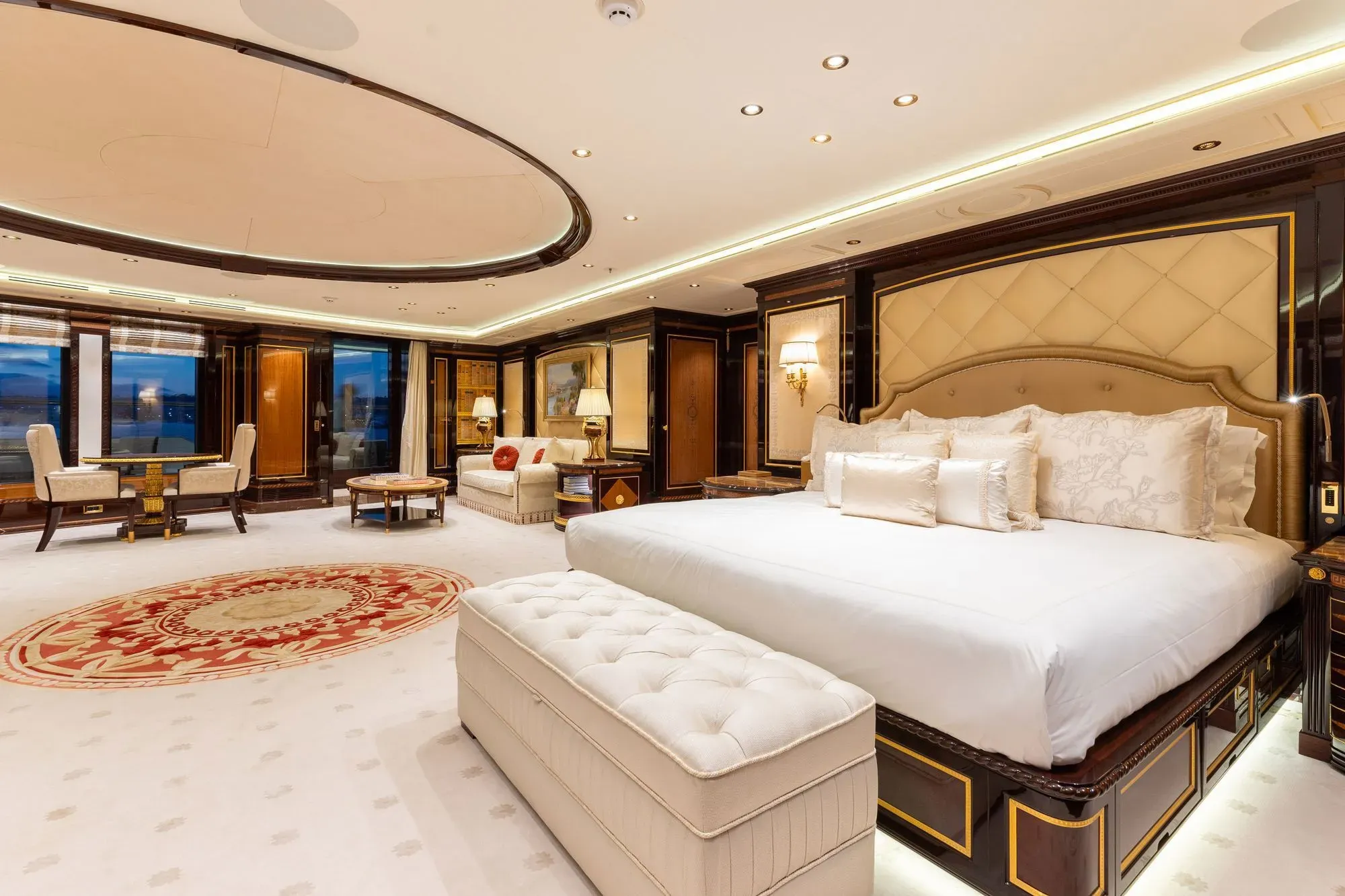 غرفة نوم فاخرة على يخت "أماديا" مع سرير كبير، أثاث أنيق، وإضاءة دافئة، تعكس الفخامة والراحة.