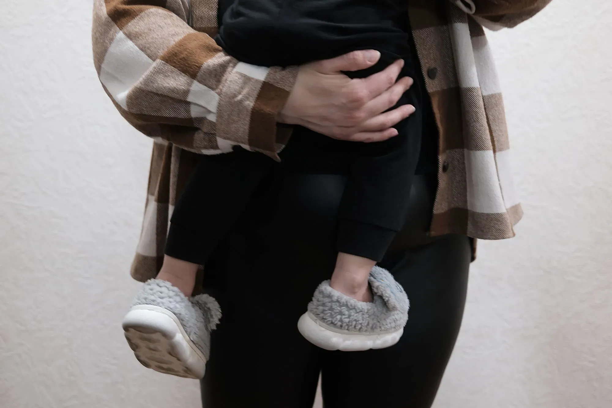 امرأة تحمل طفلاً صغيراً، ترتدي سترة مربعة، تعكس تأثيرات الحرب على العائلات الأوكرانية، وسط تزايد حالات العنف الأسري.