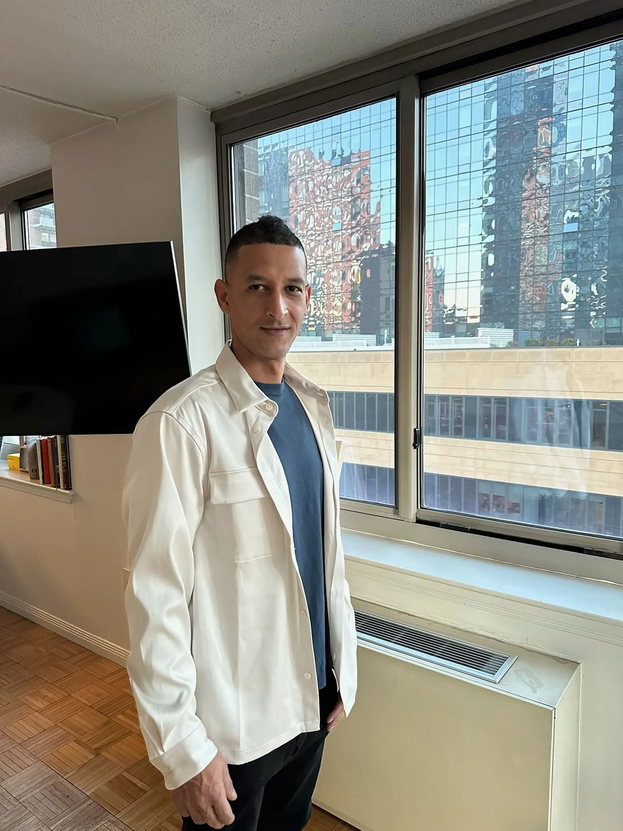 هيوري غوميز يقف بجانب نافذة في شقته بمدينة نيويورك، مستعدًا لرعاية ابنه المعاق بعد عودته من إجازة قصيرة.