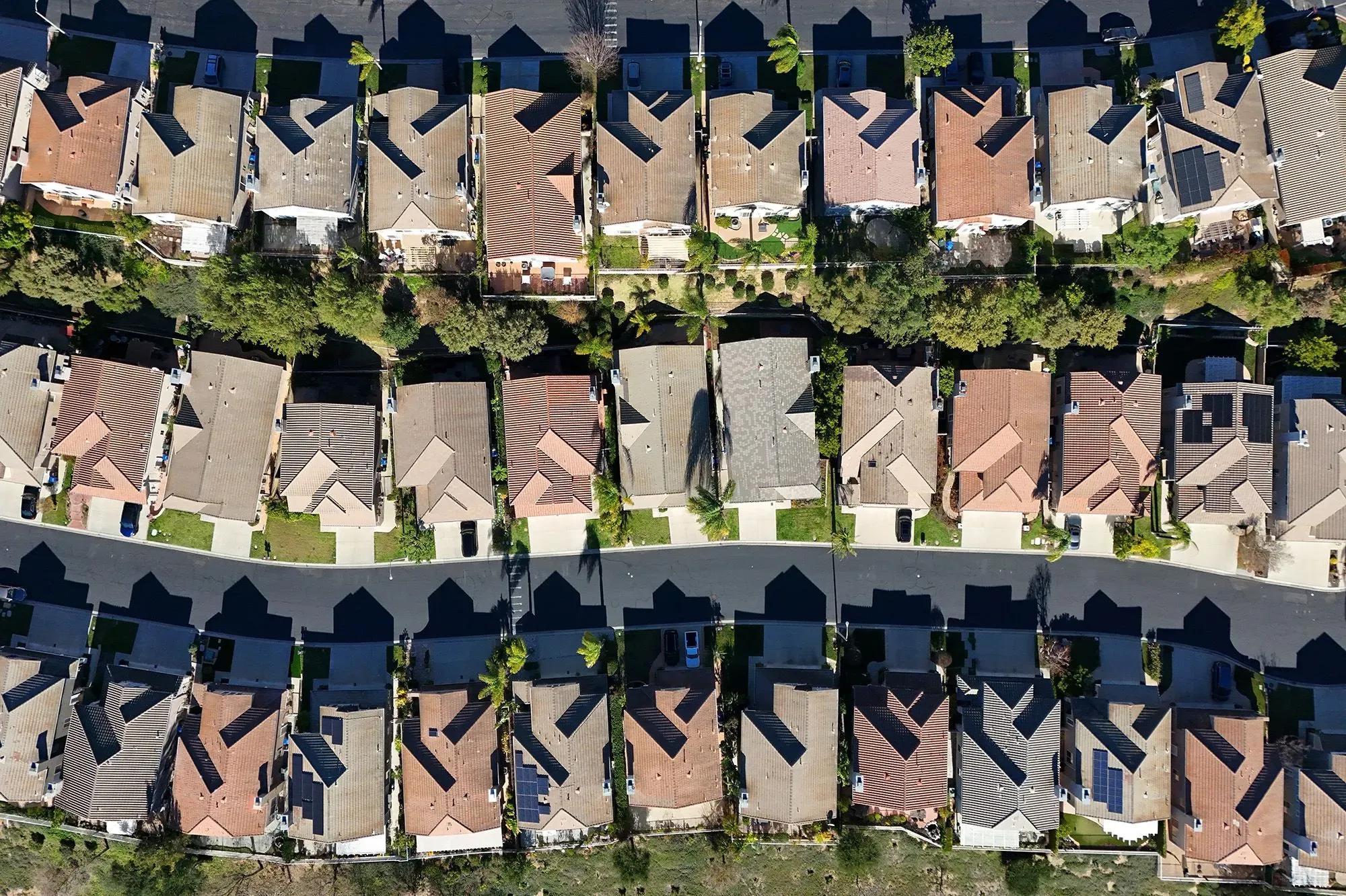 مشهد جوي لحي سكني يضم منازل متجاورة ذات أسطح ملونة، يعكس سوق العقارات وتأثيرات أسعار الرهن العقاري.