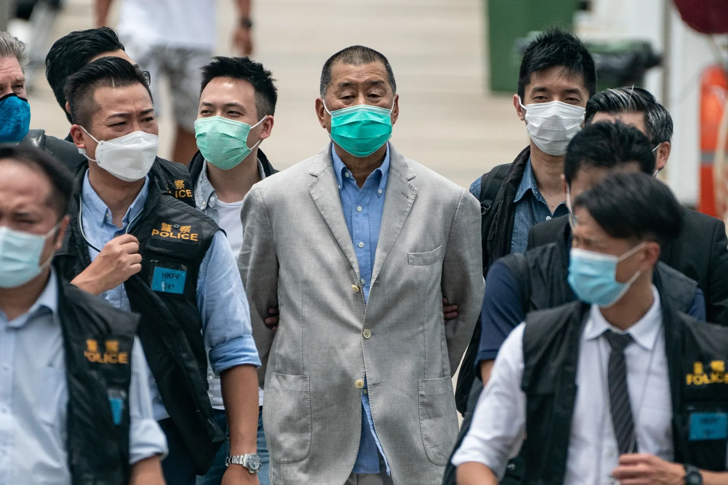 جيمي لاي، قطب الإعلام، محاطًا برجال الشرطة أثناء مغادرته المحكمة بعد الحكم عليه بالسجن 20 عامًا بتهم تتعلق بالأمن القومي في هونغ كونغ.