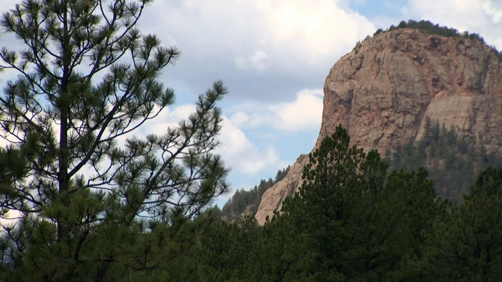 منظر لجبال روكي الجنوبية في كولورادو، مع أشجار دائمة الخضرة تتخللها صخور جرانيتية ضخمة تحت سماء غائمة.