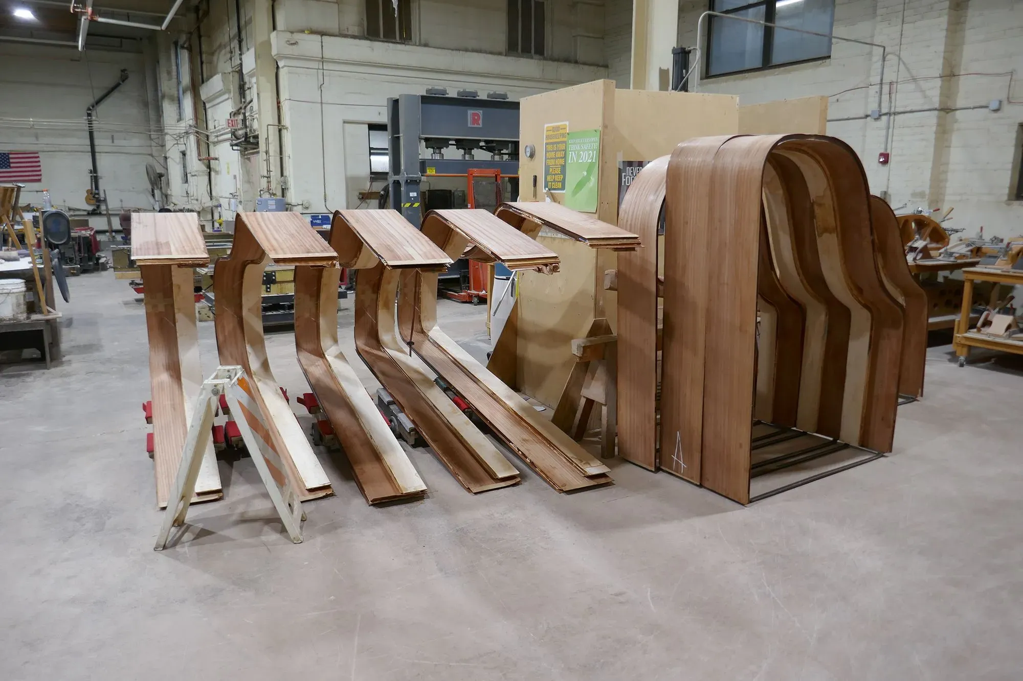 قطع خشبية منحوتة تُستخدم في تصنيع البيانو، مع أدوات عمل في مصنع شتاينواي وأولاده، تعكس الحرفية العالية في صناعة الآلات الموسيقية.