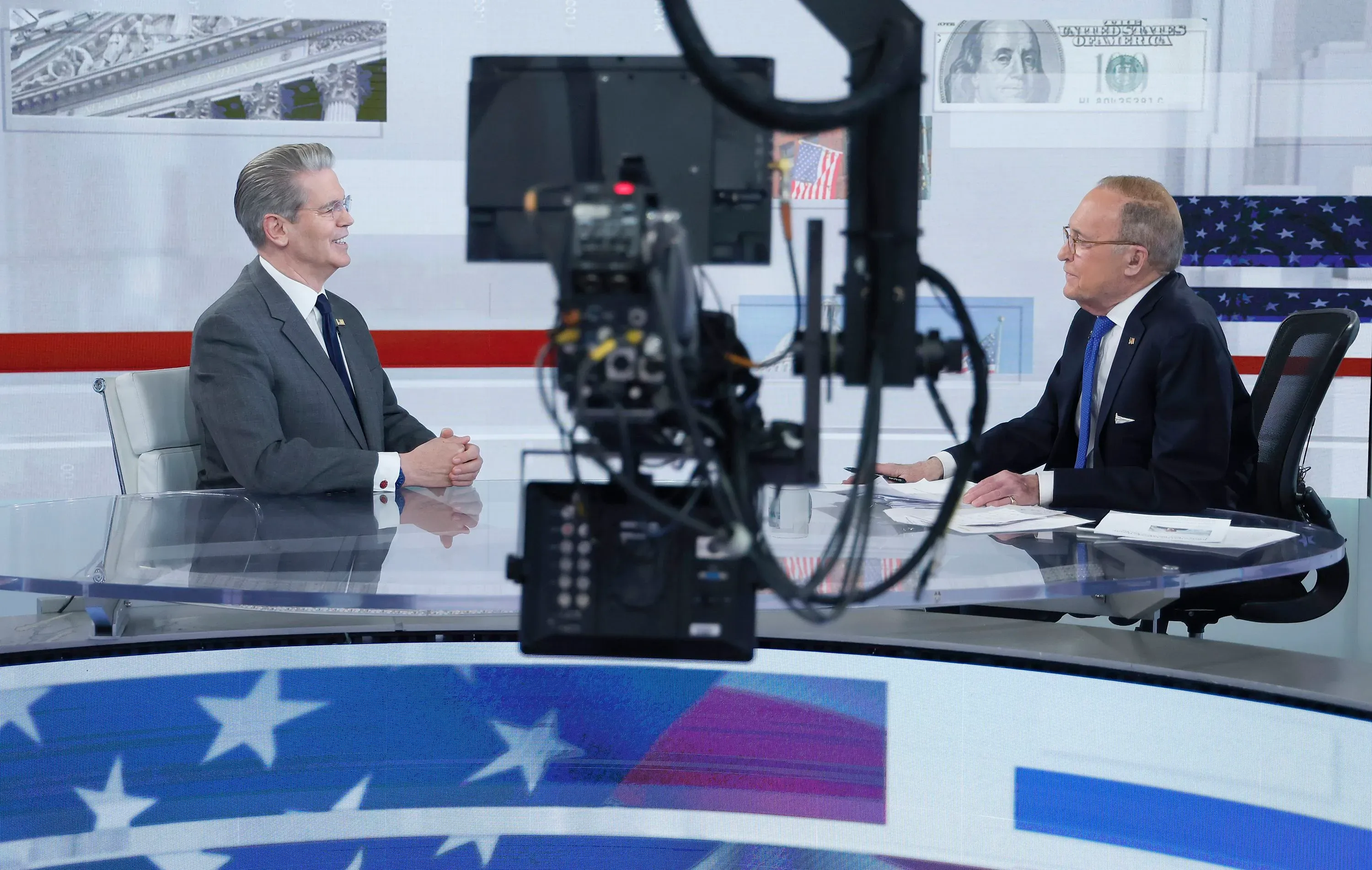 مقابلة تلفزيونية في استوديو مع سكوت بيسنت، وزير الخزانة الأمريكي، يتحدث مع لاري كودلو حول السياسة الاقتصادية والإجراءات المرتبطة بترامب.