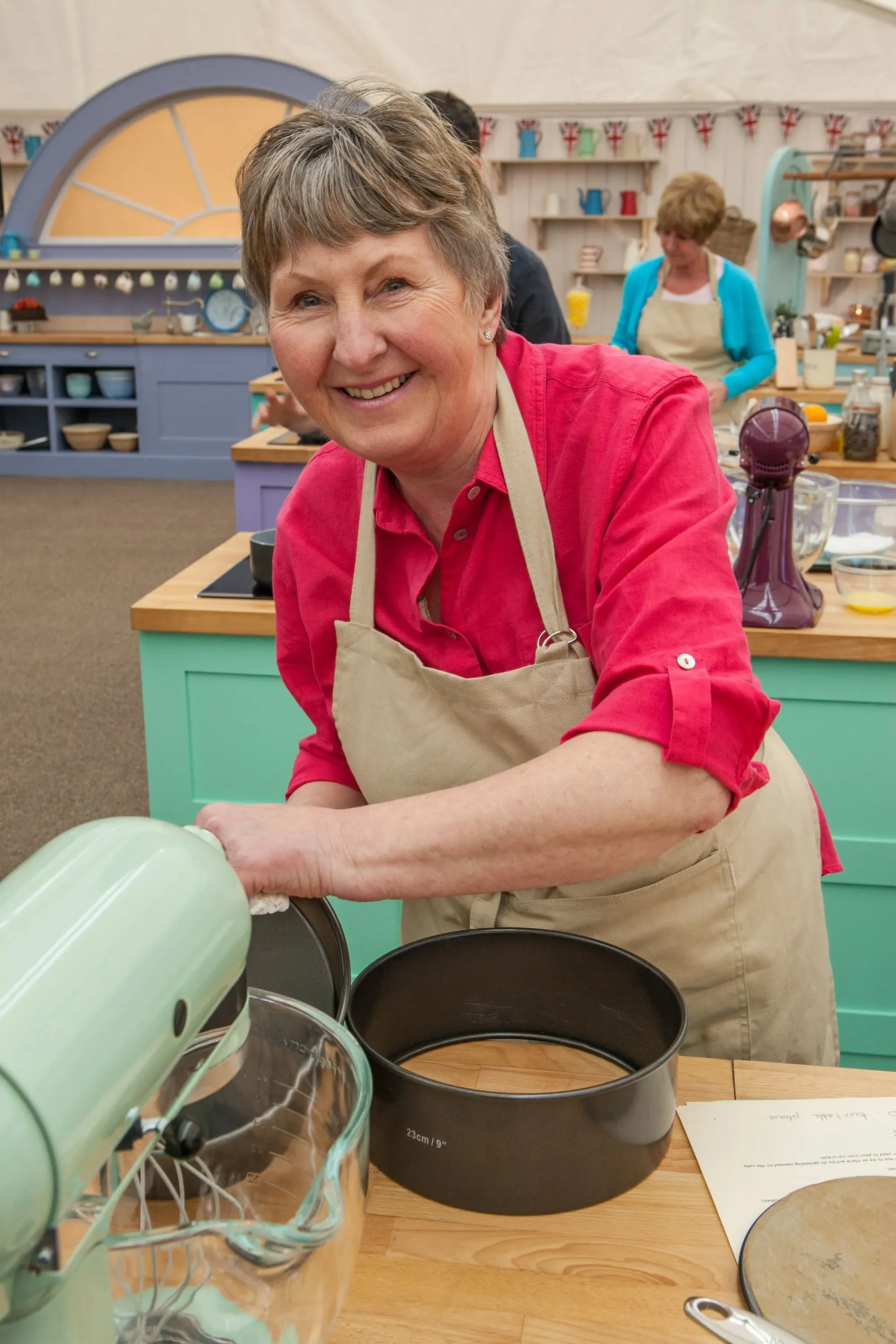فال ستونز، نجمة برنامج "Great British Baking Show"، تبتسم أثناء تحضيرها للخبز في مطبخ، مما يعكس شغفها بالخبز وصحة العظام.