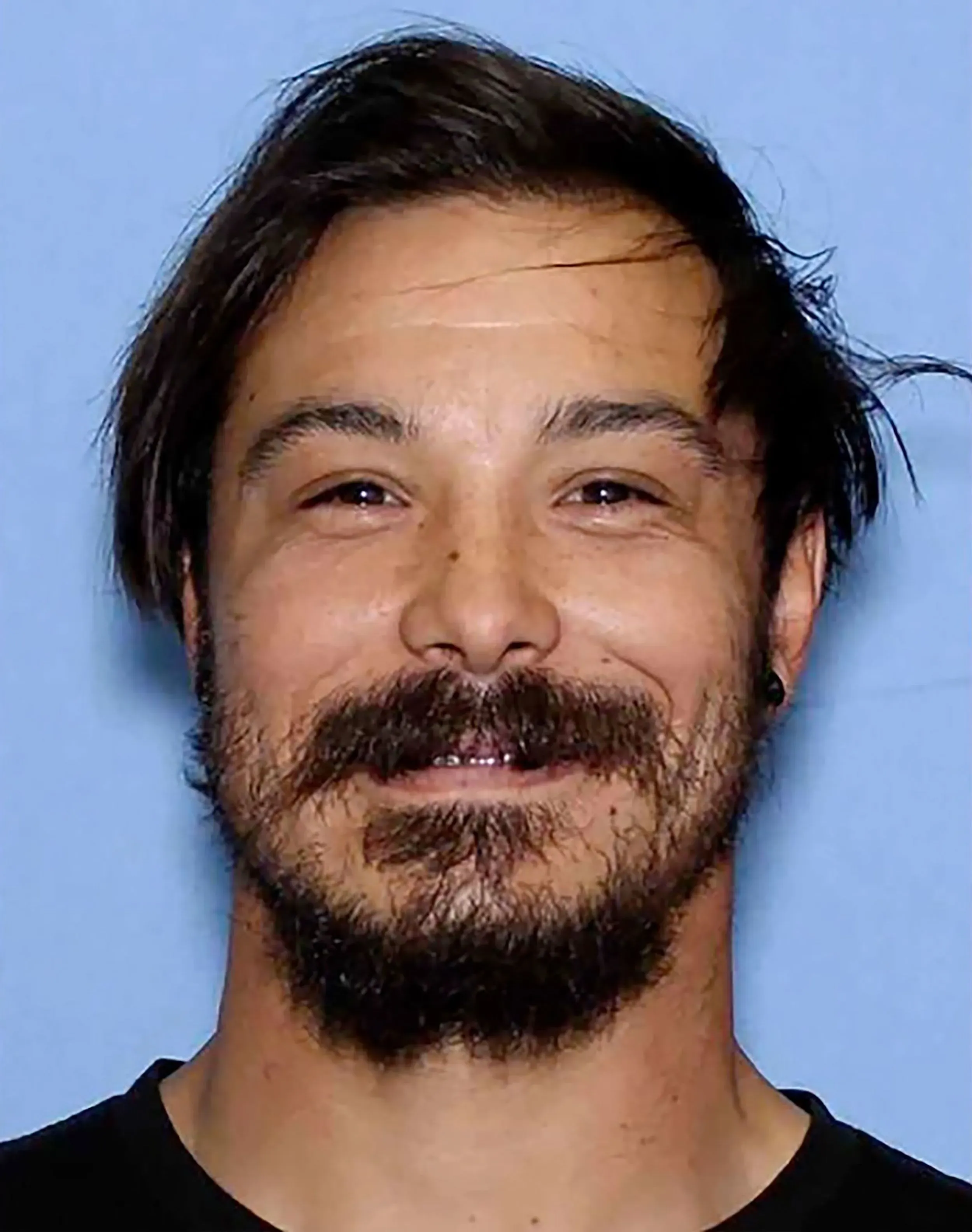 صورة لرجل ملتحٍ ذو شعر بني داكن، يبدو مبتسمًا. يُعتقد أنه ترافيس ديكر، المطلوب في قضية مقتل بناته الثلاث في واشنطن.