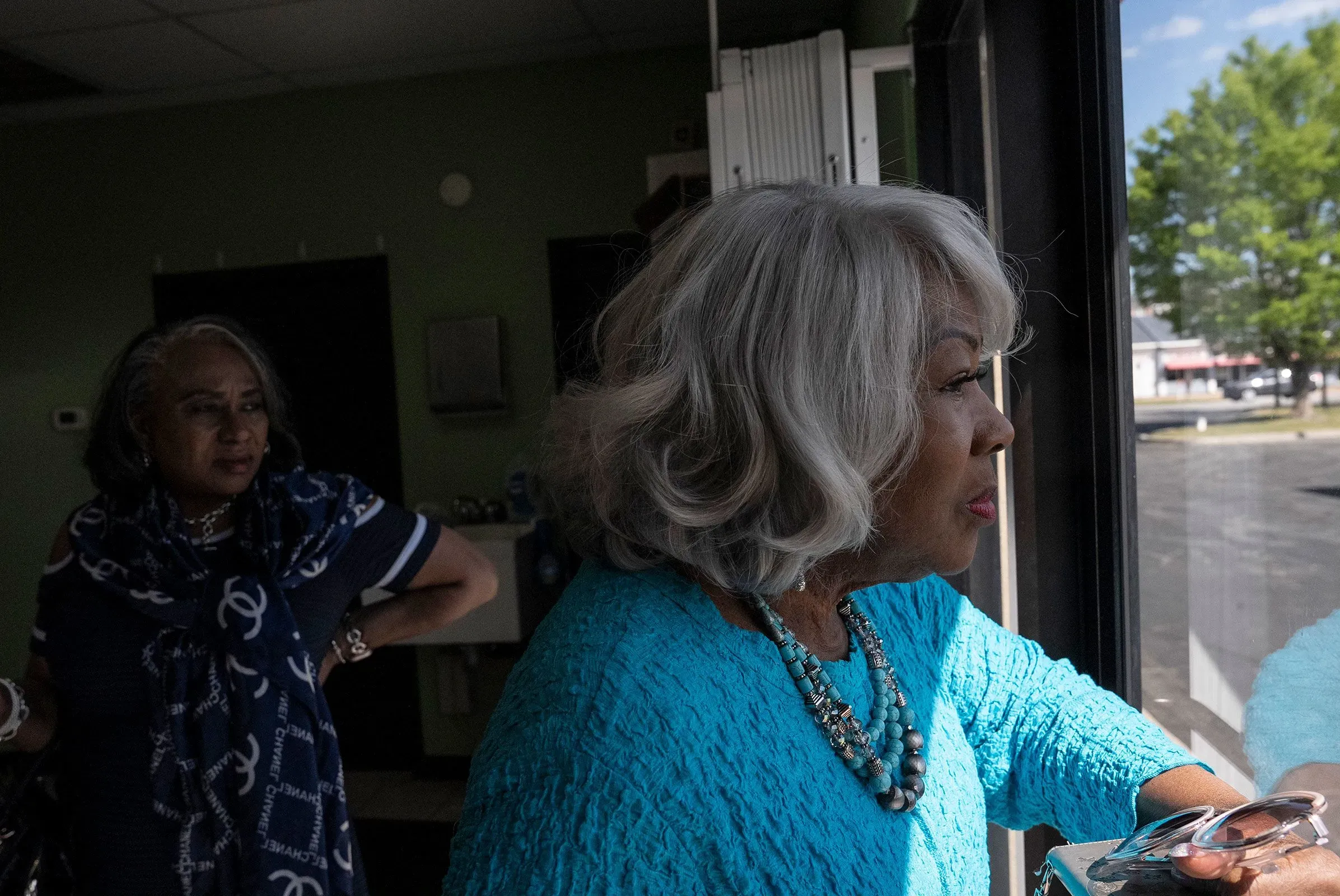 لويز لوكاس، السياسية البارزة في فرجينيا، تنظر من نافذة بينما تتحدث مع امرأة أخرى، مع التركيز على أهمية التغيير السياسي في الولاية.