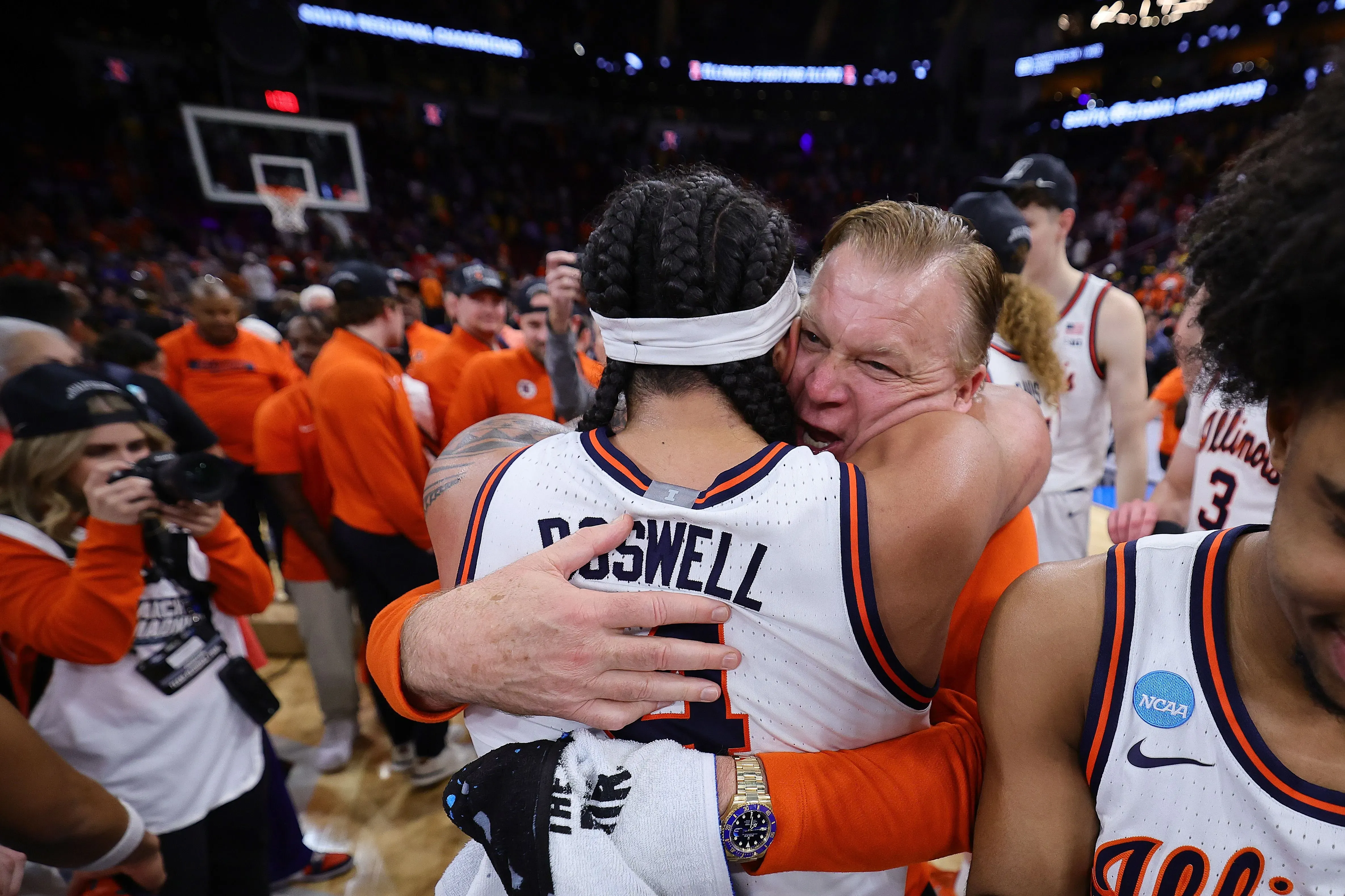 احتفال حماسي بين مدرب إلينوي براد أندروود واللاعب ماركوس دوماسك بعد الفوز في مباراة مهمة، مع جمهور متحمس في الخلفية.