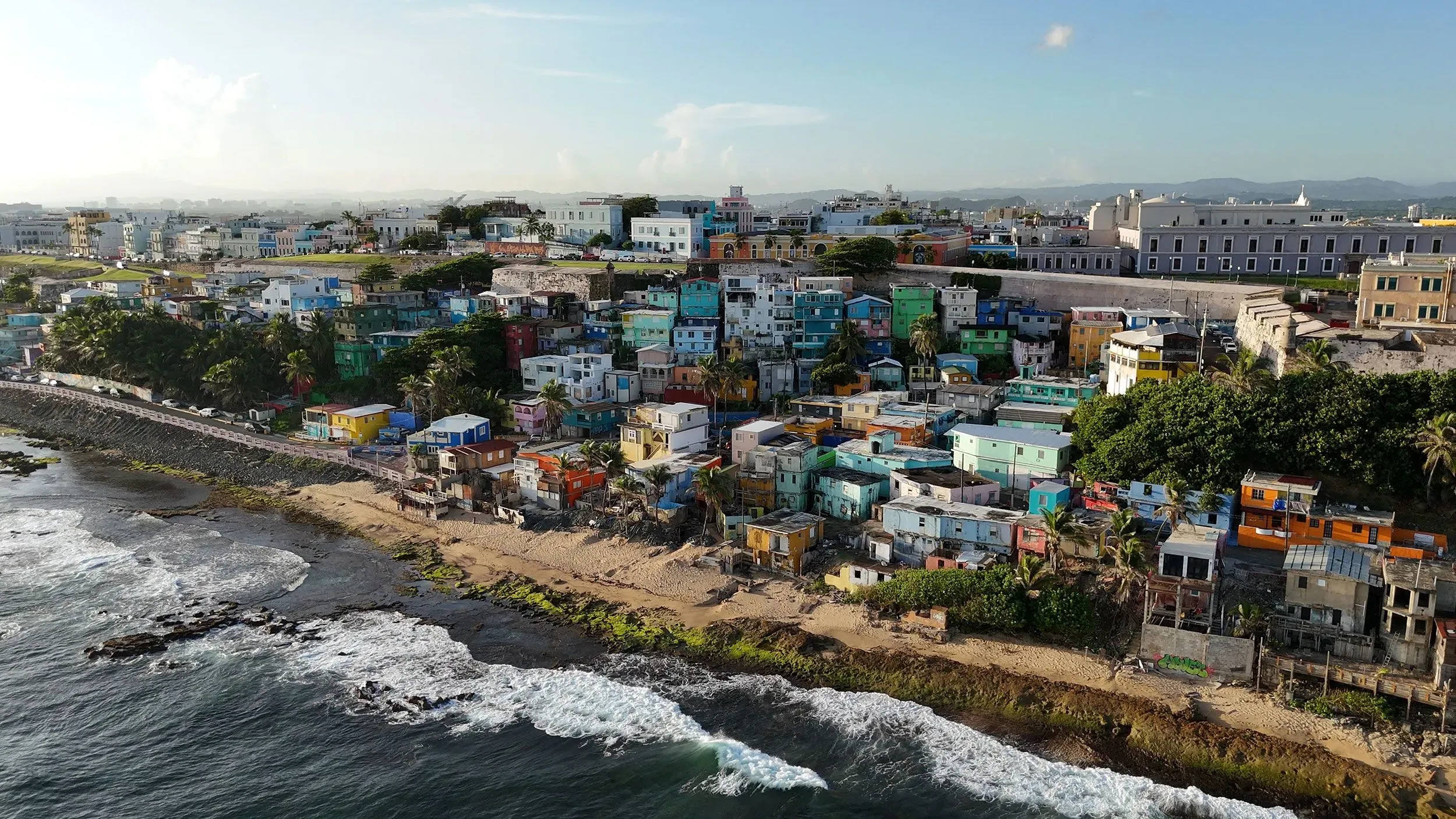 منظر جوي لمدينة سان خوان في بورتوريكو، يظهر المنازل الملونة على الساحل، مما يعكس تأثير جولة باد باني على السياحة المحلية.