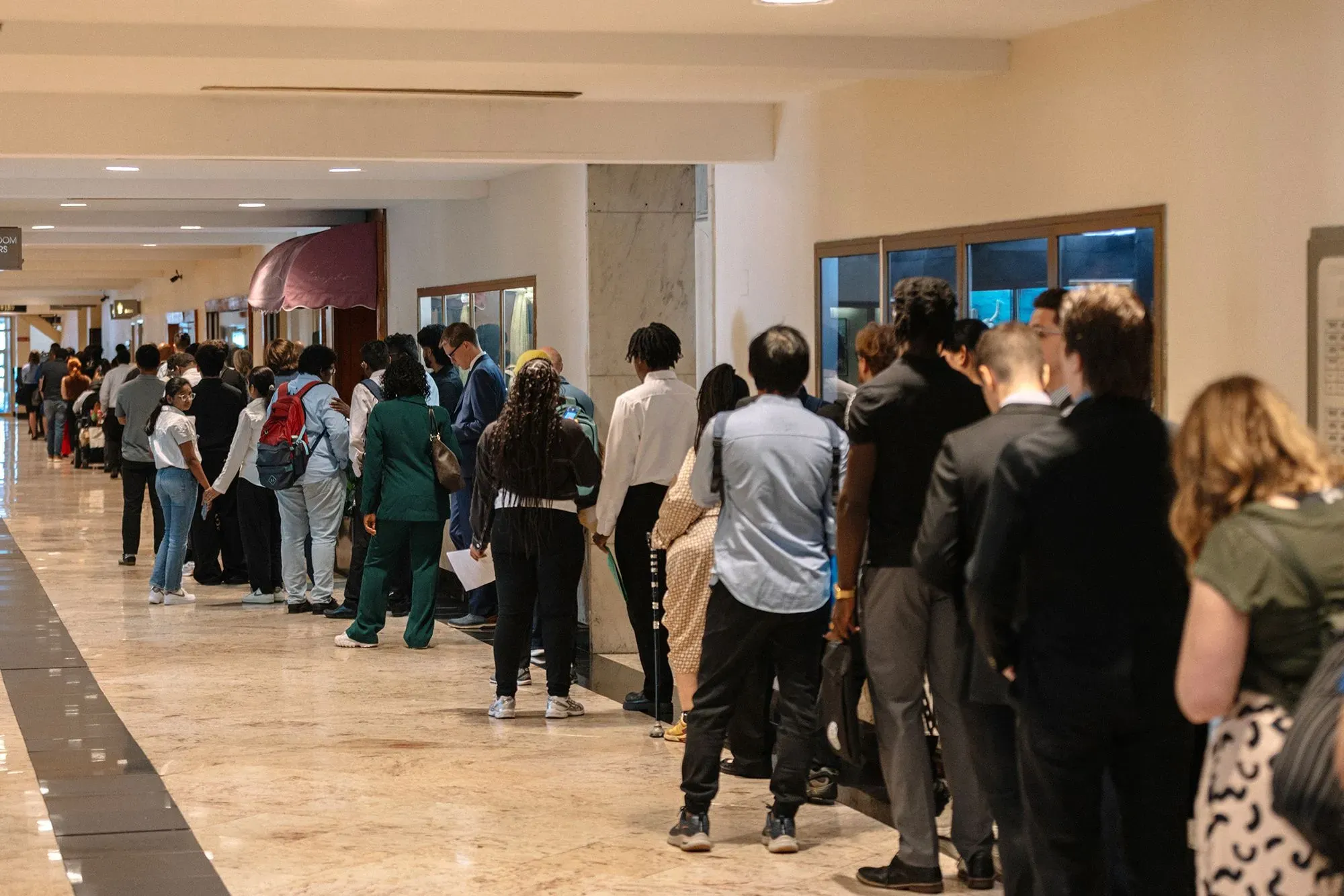 طابور طويل من الباحثين عن عمل في ممر عمل، يعكس التحديات الاقتصادية الحالية في الولايات المتحدة وارتفاع معدل البطالة.