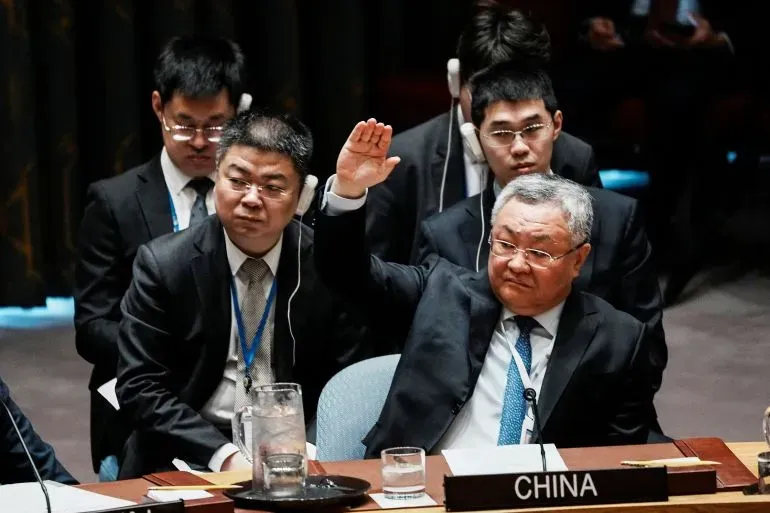 مندوب الصين في مجلس الأمن يرفع يده للتصويت، محاطًا بزملائه، في سياق مناقشات حول النزاع في الشرق الأوسط.