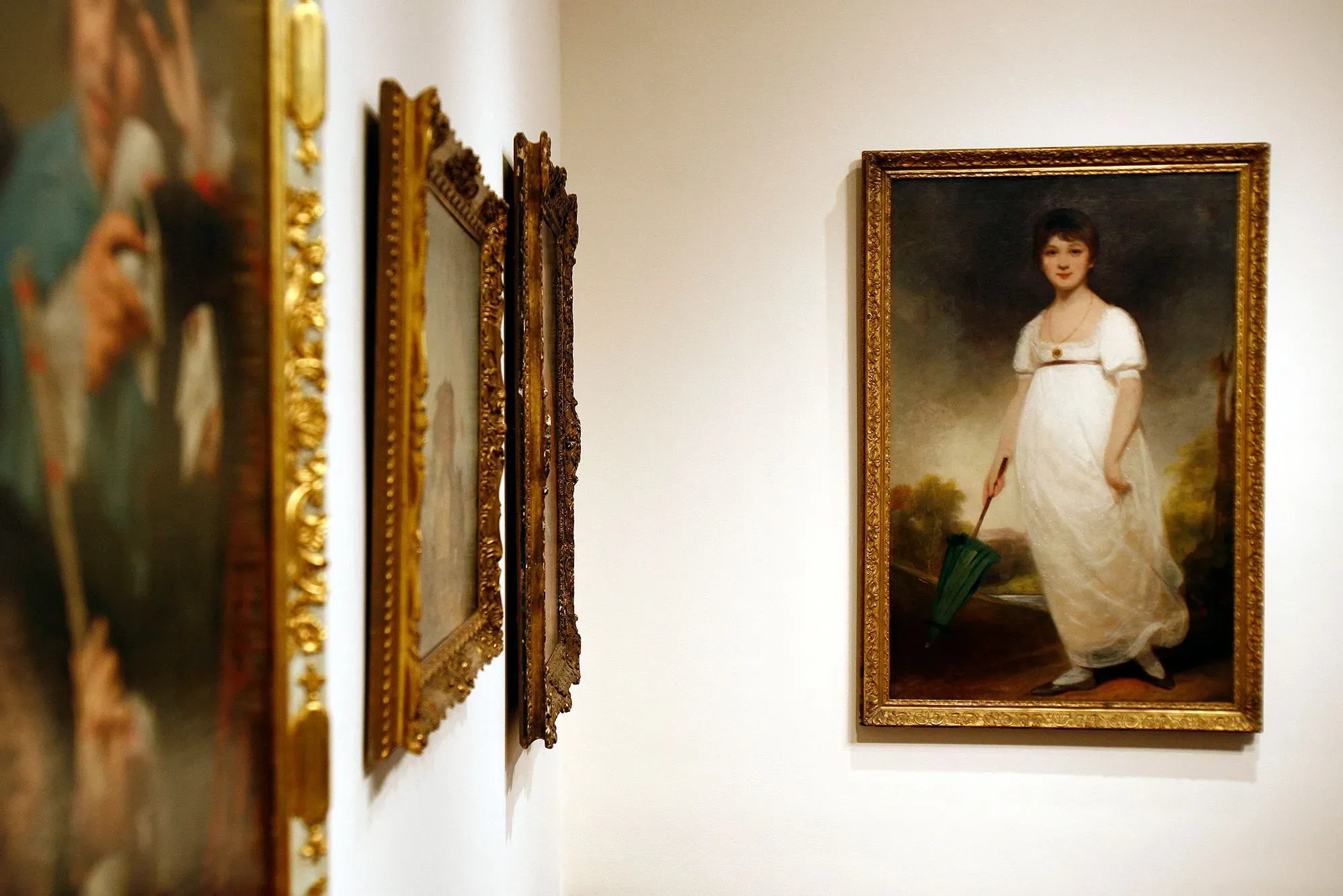 لوحة لجين أوستن تظهر فيها ترتدي فستانًا أبيض وتستند إلى مظلة خضراء، محاطة بإطارات ذهبية لصور أخرى، تعكس تاريخها الأدبي.