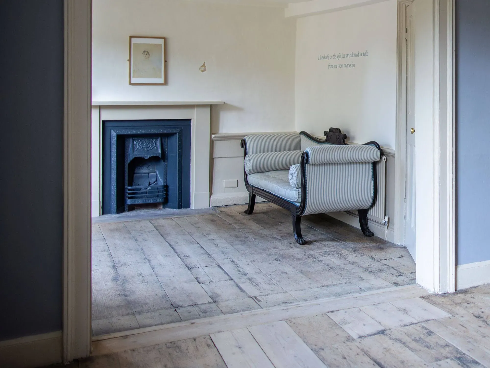 غرفة بسيطة تحتوي على أريكة مزخرفة ومدفأة، تشير إلى الأيام الأخيرة لجين أوستن في منزلها، حيث توفيت عام 1817.