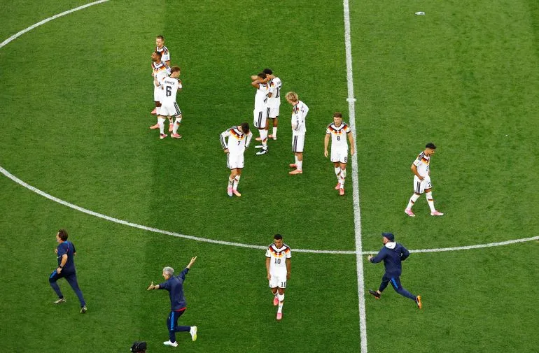 لاعبو منتخب ألمانيا لكرة القدم يظهرون علامات خيبة الأمل بعد تعادلهم مع باراغواي في كأس العالم، مع مدربيهم على أرض الملعب.