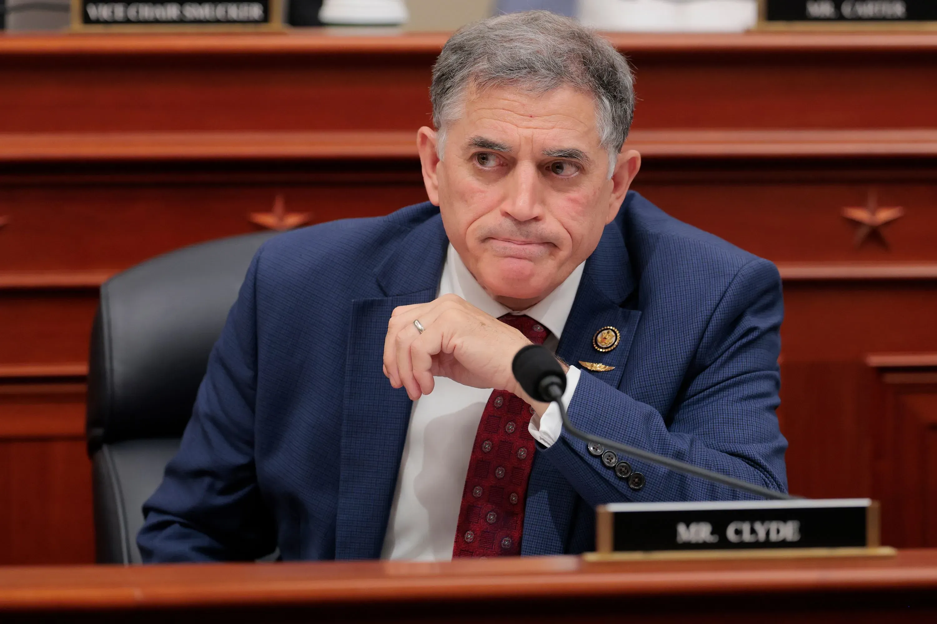 وجه رجل في بدلة زرقاء يجلس أمام ميكروفون، مع تعبير جاد، في جلسة استماع رسمية تتعلق بقوانين الهجرة.