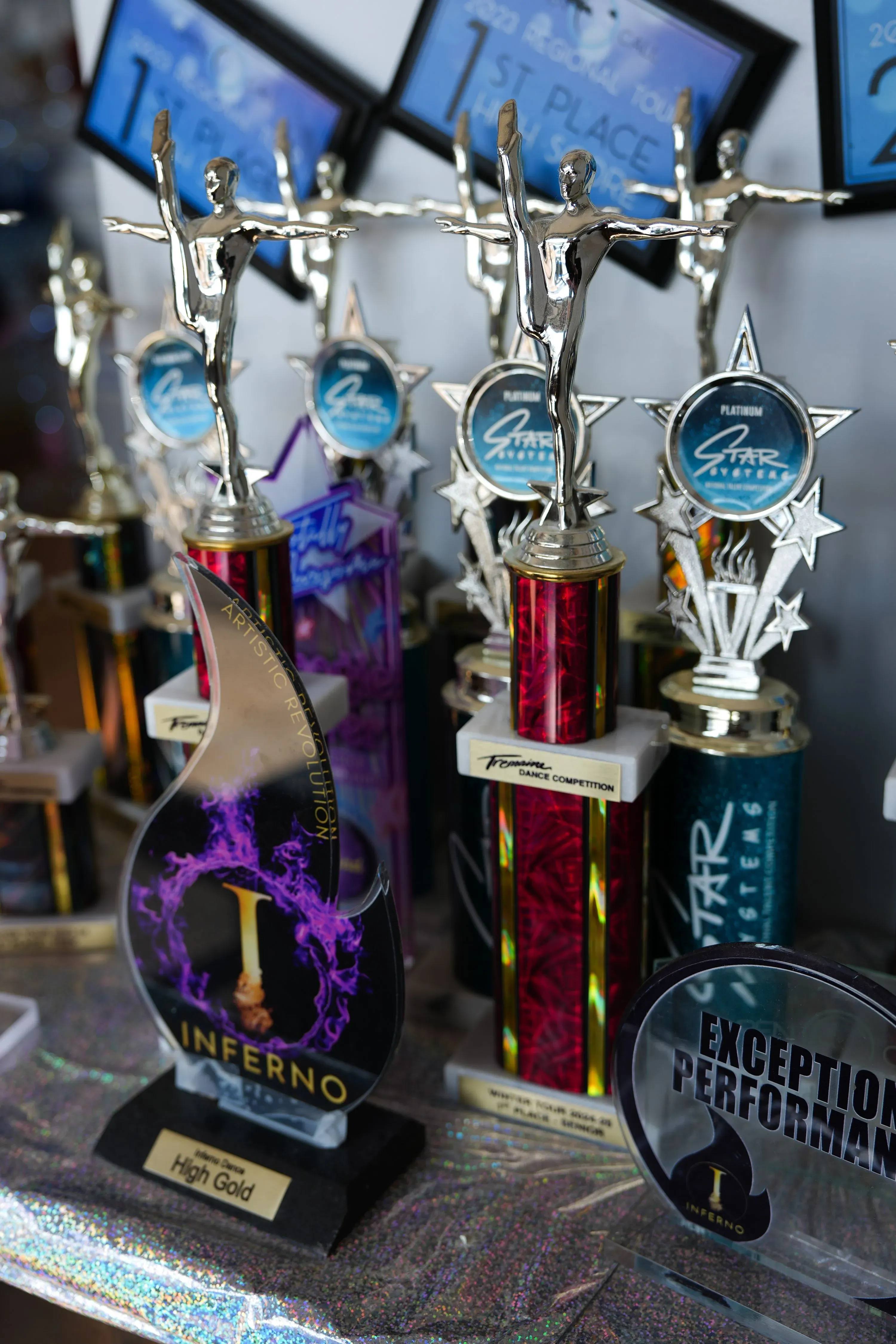 جوائز رقص متنوعة تشمل تماثيل فضية وميداليات، مع شهادات تفيد بالفوز بالمراكز الأولى في مسابقات الرقص.