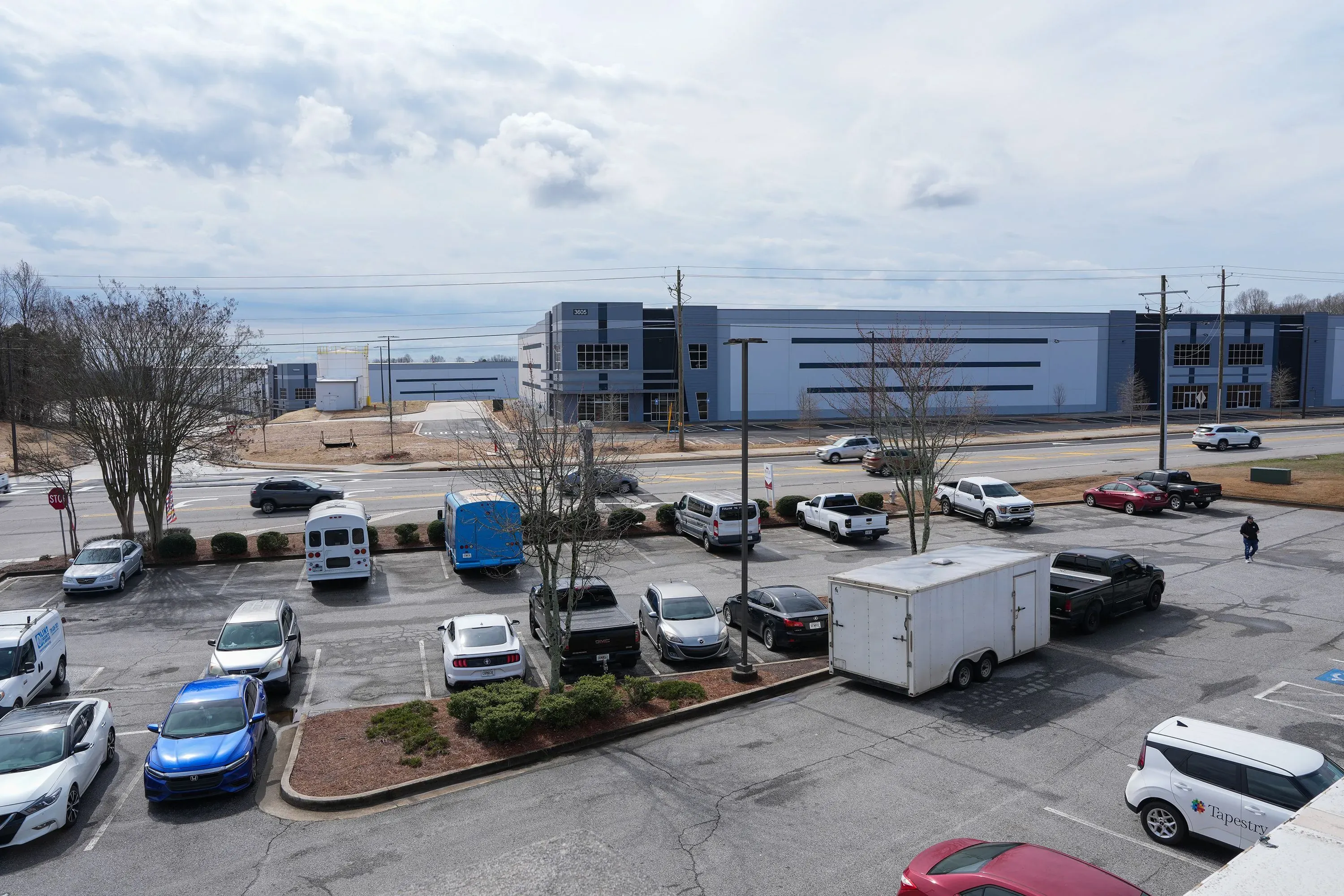 مستودع كبير في أوكوود، جورجيا، مع سيارات متوقفة في المقدمة، يُظهر المخاوف بشأن تحويله إلى مركز احتجاز للمهاجرين.