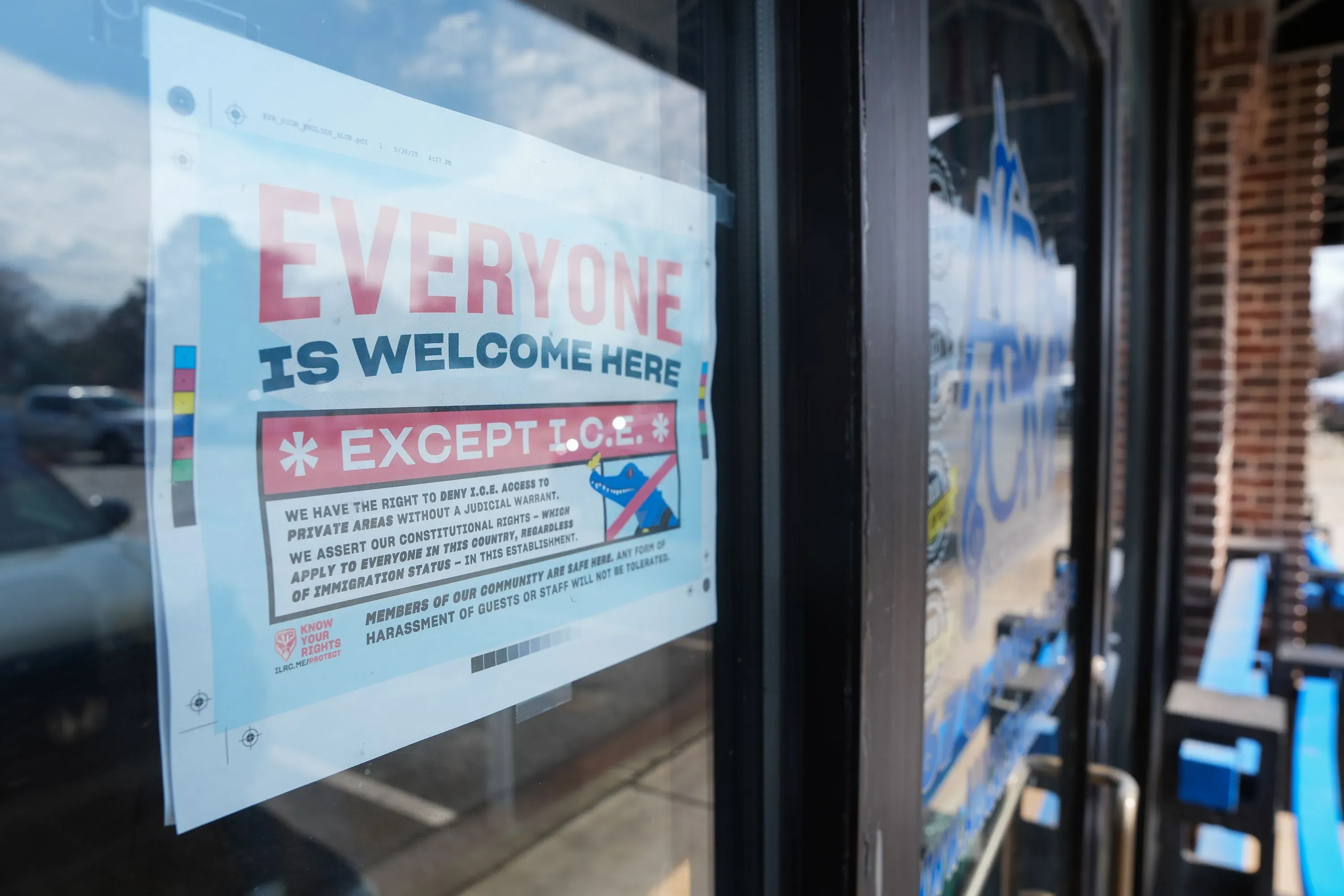 ملصق على نافذة استوديو الرقص يرحب بالجميع باستثناء إدارة الهجرة والجمارك، مما يعكس القلق المحلي بشأن خطط احتجاز المهاجرين.