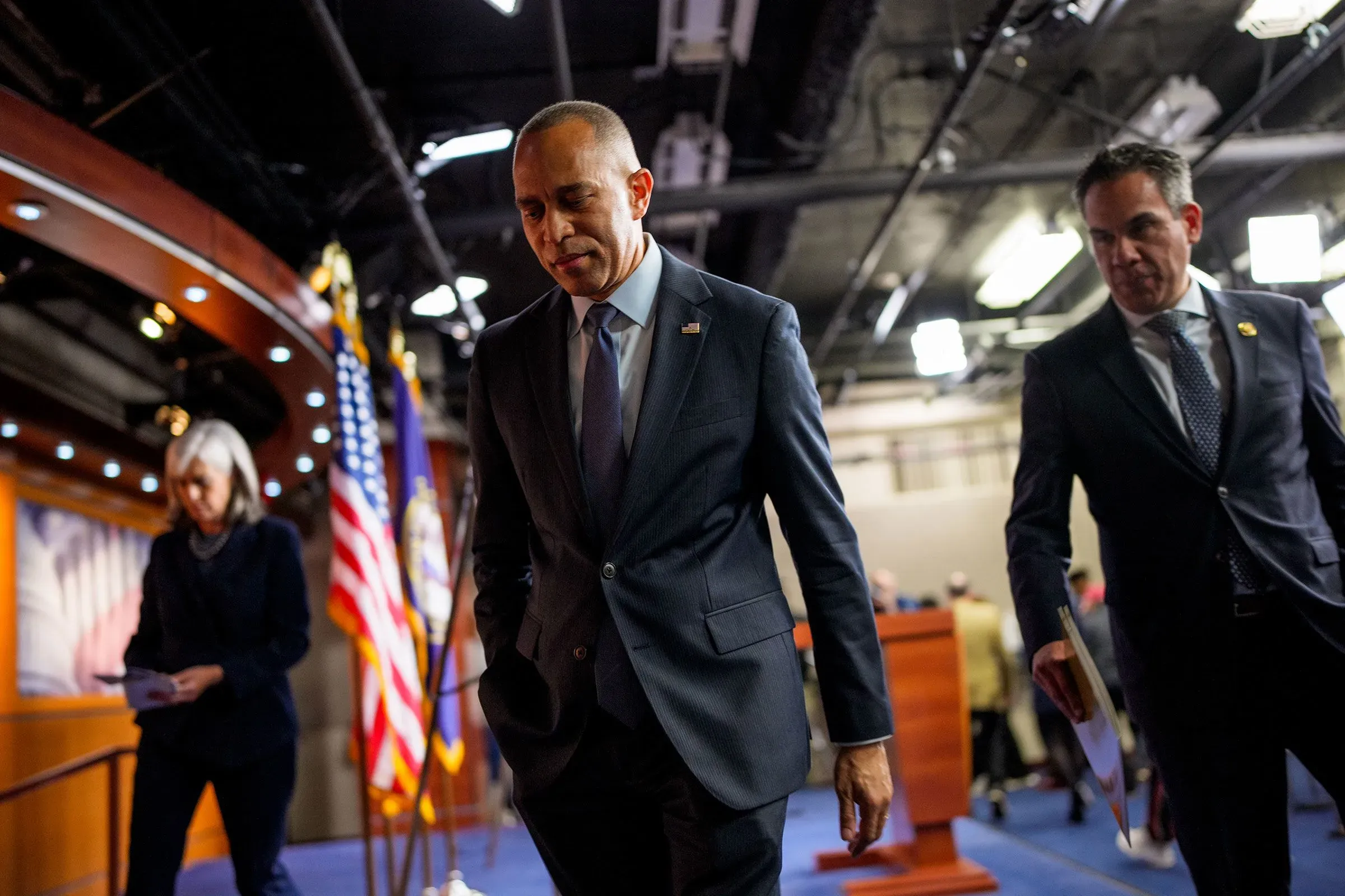 زعيم الحزب الديمقراطي حكيم جيفريز وزعيم الحزب الجمهوري مايك جونسون يغادران مؤتمرًا صحفيًا مع أعلام الولايات المتحدة خلفهما، في سياق التوترات السياسية الحالية.