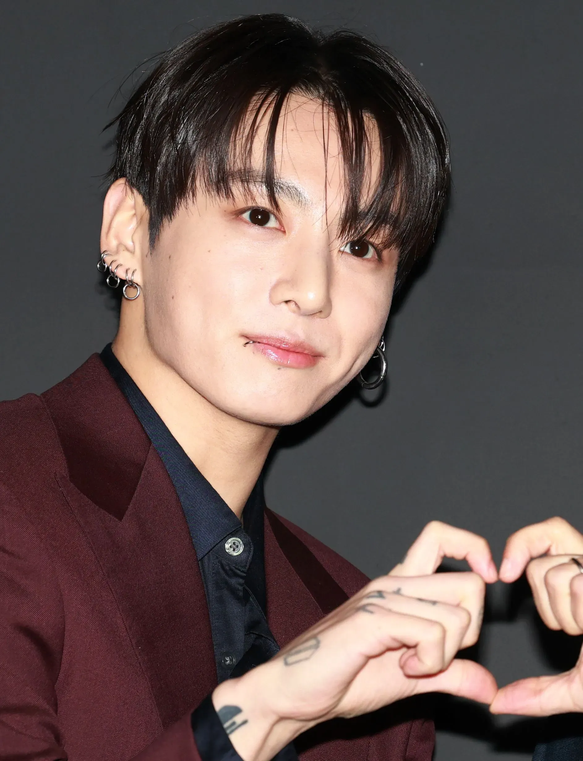 شخصية شابة من فرقة BTS تعبر عن حبها لجمهورها بإيماءة قلب، مما يعكس العلاقة القوية بين الفنانين ومعجبيهم في أمريكا اللاتينية.